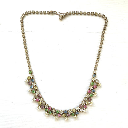 A vintage necklace adorned with white enamel flowers and colourful rhinestones.白いエナメルのお花とカラフルなラインストーンが並んだネックレス。