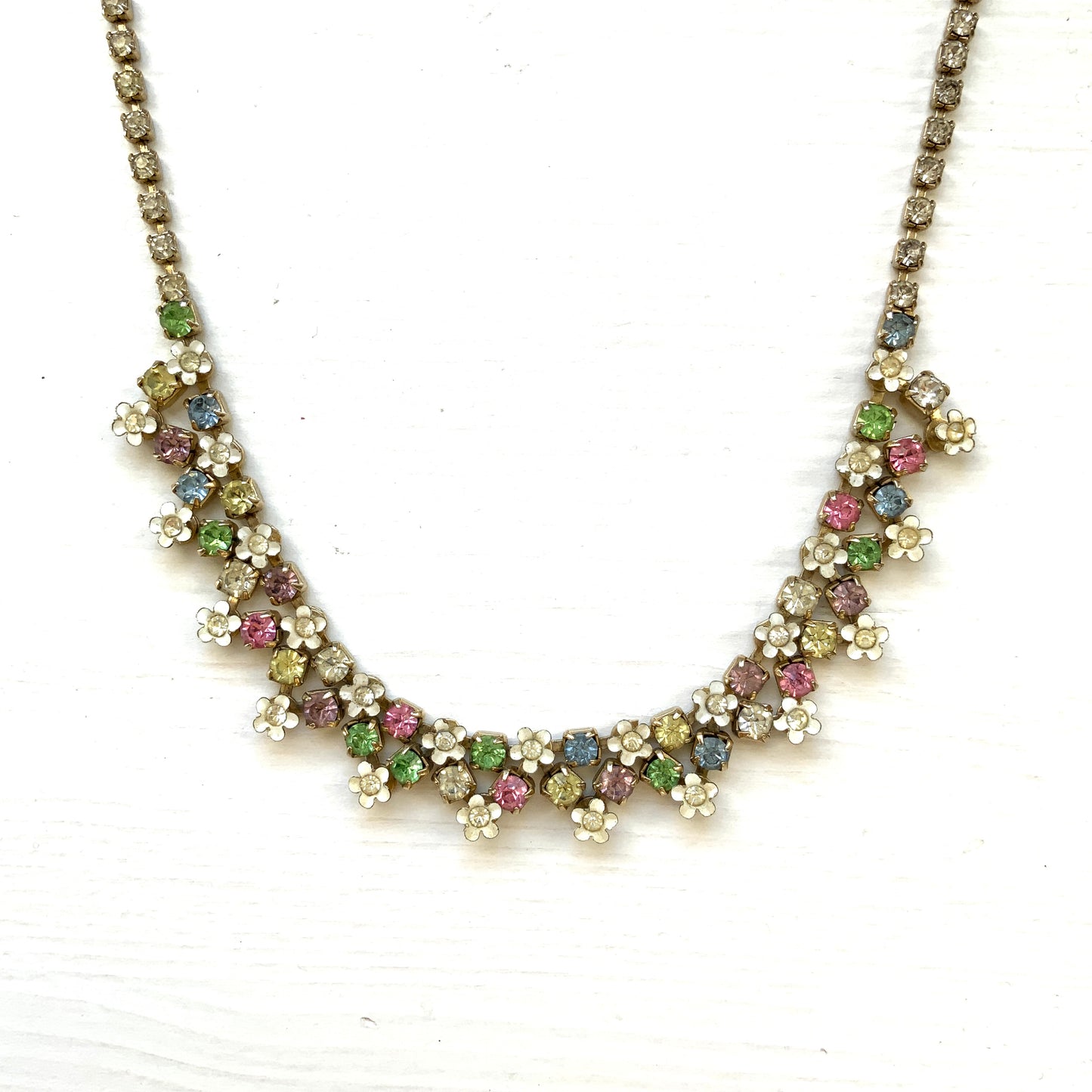 A vintage necklace adorned with white enamel flowers and colourful rhinestones.白いエナメルのお花とカラフルなラインストーンが並んだネックレス。