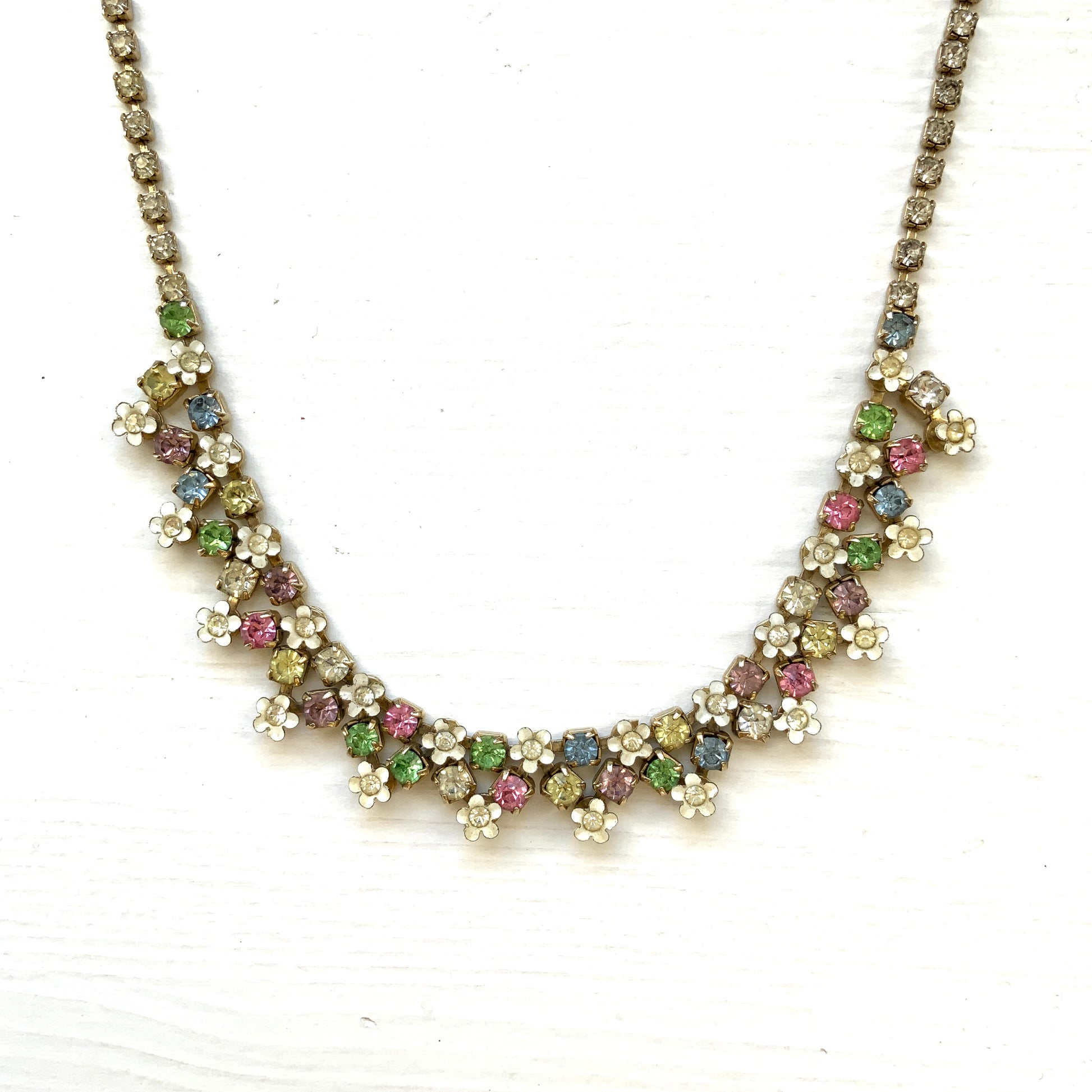 A vintage necklace adorned with white enamel flowers and colourful rhinestones.白いエナメルのお花とカラフルなラインストーンが並んだネックレス。