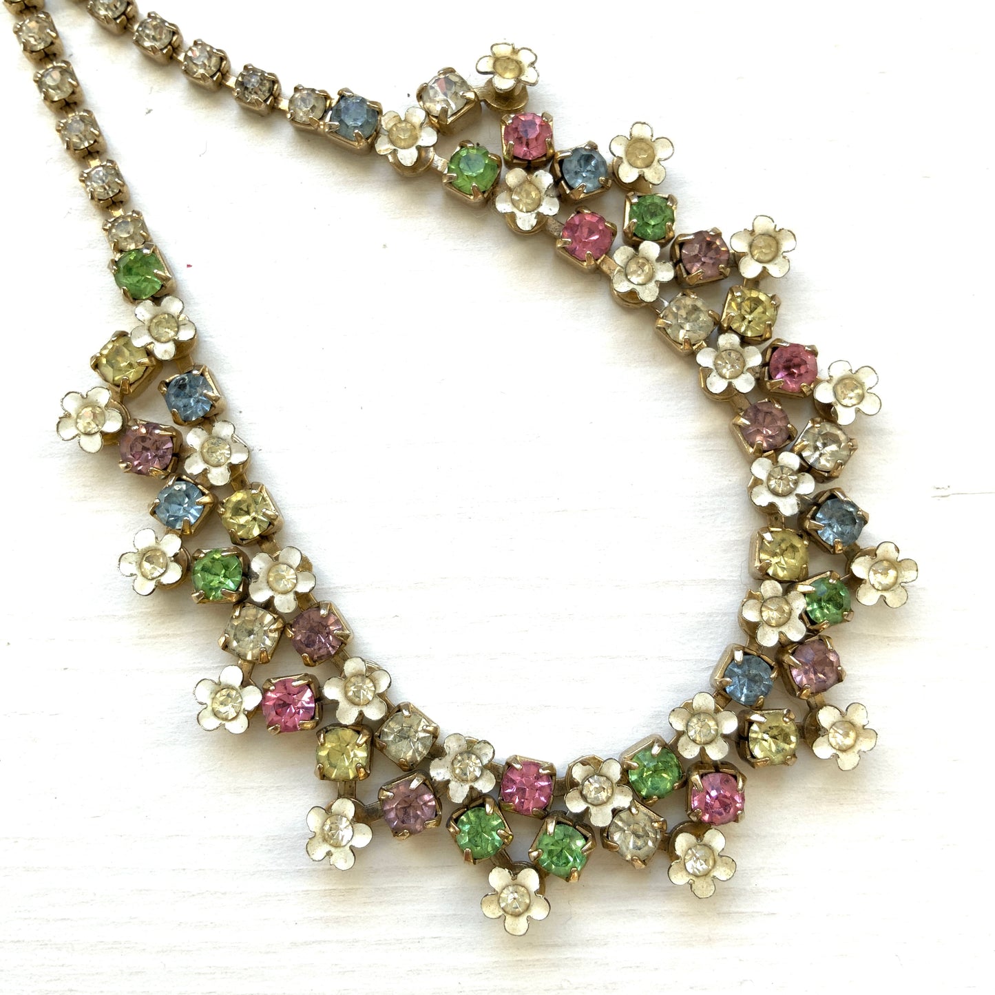 A vintage necklace adorned with white enamel flowers and colourful rhinestones.白いエナメルのお花とカラフルなラインストーンが並んだネックレス。
