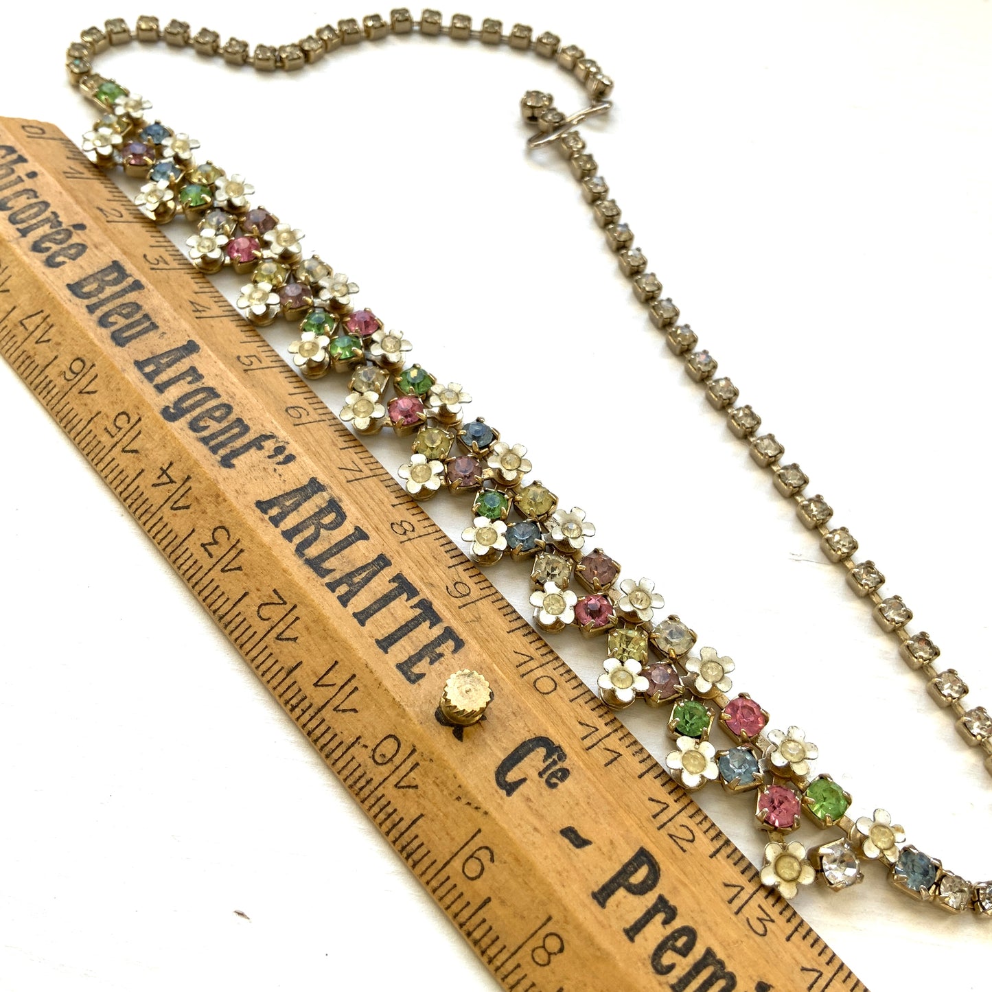 A vintage necklace adorned with white enamel flowers and colourful rhinestones.白いエナメルのお花とカラフルなラインストーンが並んだネックレス。