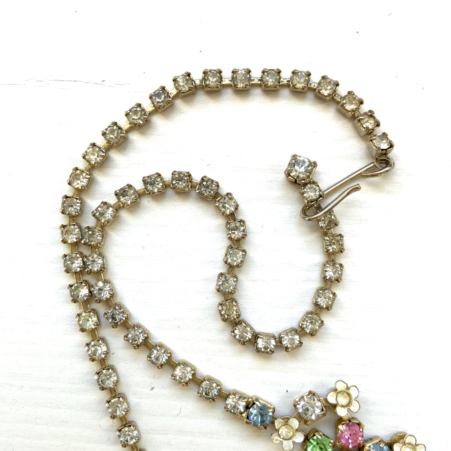 A vintage necklace adorned with white enamel flowers and colourful rhinestones.白いエナメルのお花とカラフルなラインストーンが並んだネックレス。