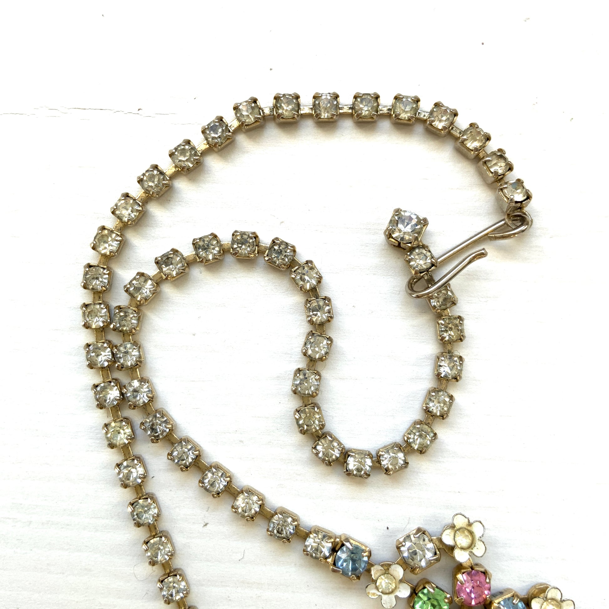 A vintage necklace adorned with white enamel flowers and colourful rhinestones.白いエナメルのお花とカラフルなラインストーンが並んだネックレス。