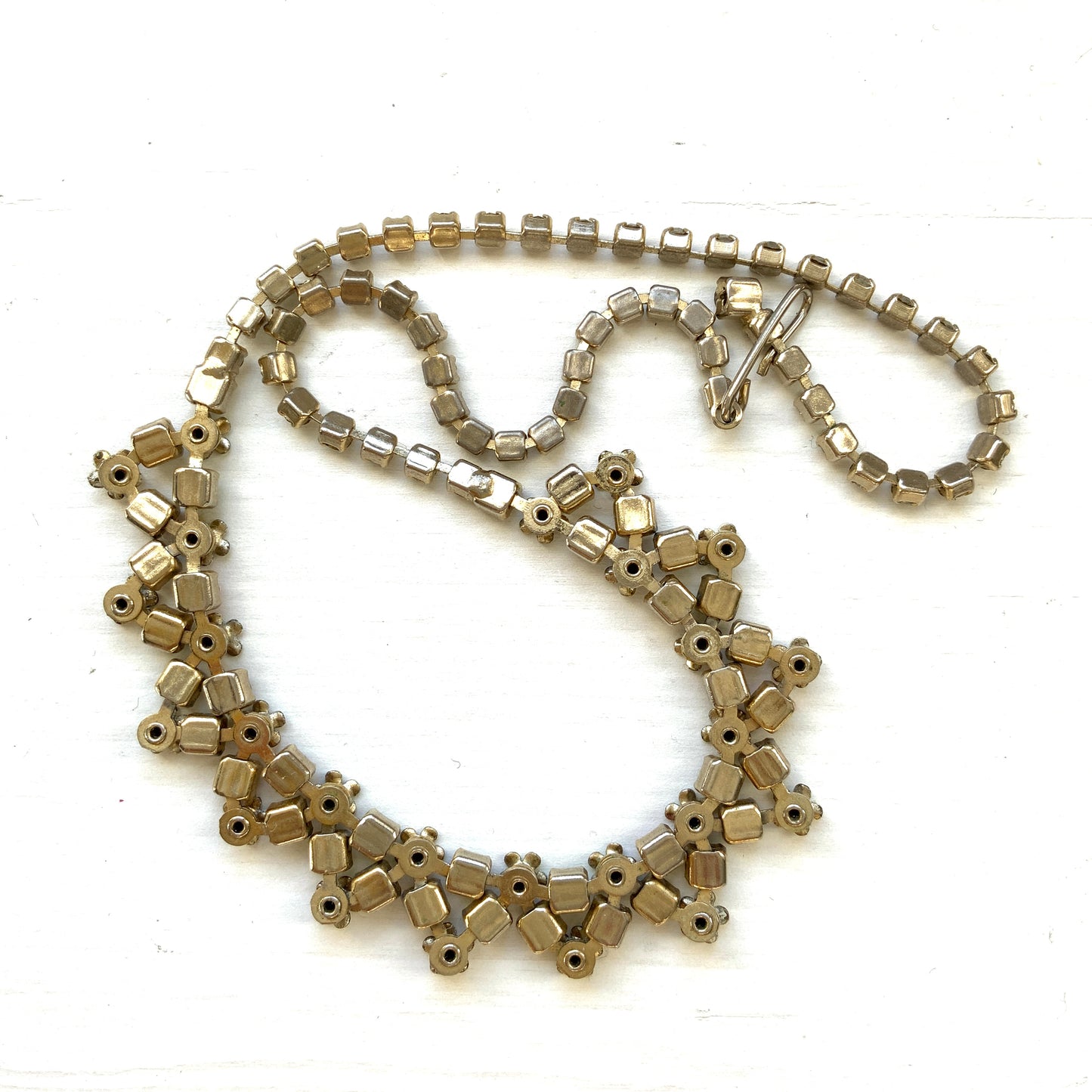 A vintage necklace adorned with white enamel flowers and colourful rhinestones.白いエナメルのお花とカラフルなラインストーンが並んだネックレス。