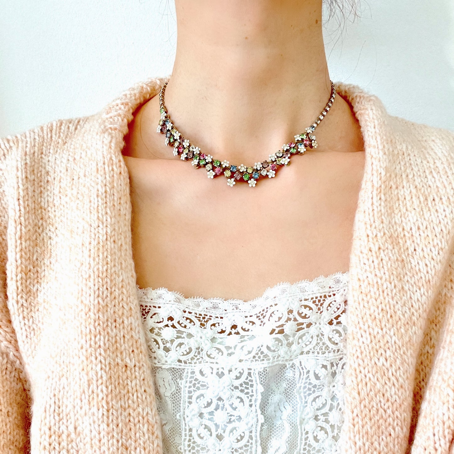 A vintage necklace adorned with white enamel flowers and colourful rhinestones.白いエナメルのお花とカラフルなラインストーンが並んだネックレス。