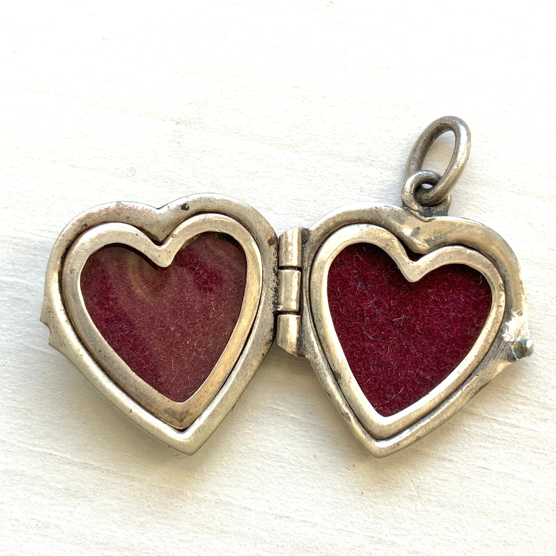 A silver heart locket featuring white guilloché enamel with a very subtle pale mint-green undertone, decorated with a rose motif.  ごく淡いミントグリーンのシェードを含んだホワイトギヨシェエナメルに、薔薇のモチーフが描かれたシルバーのハートロケット。