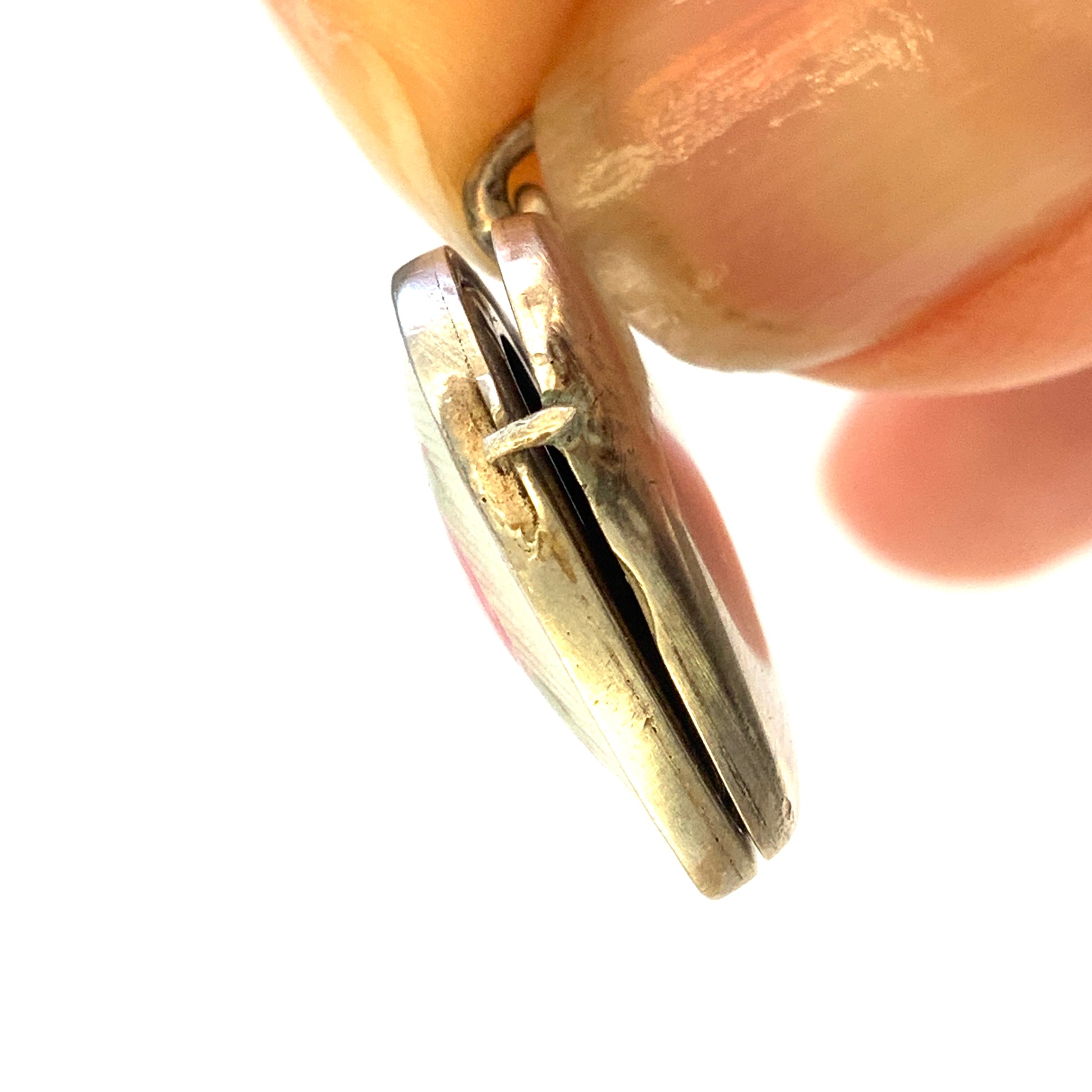 A silver heart locket featuring white guilloché enamel with a very subtle pale mint-green undertone, decorated with a rose motif.  ごく淡いミントグリーンのシェードを含んだホワイトギヨシェエナメルに、薔薇のモチーフが描かれたシルバーのハートロケット。