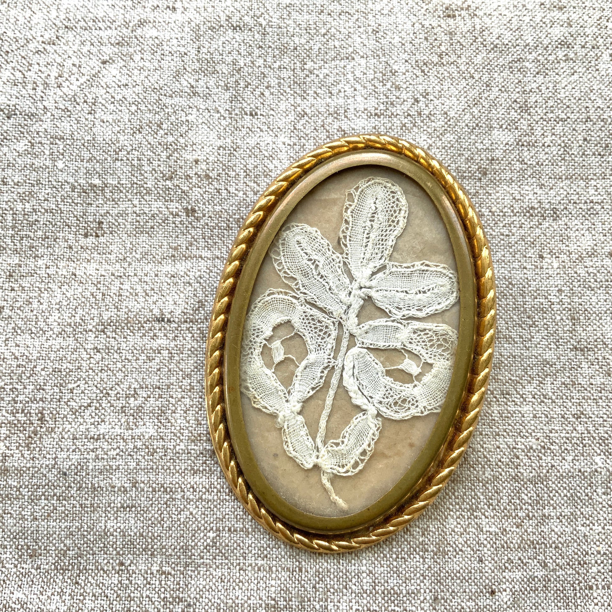 A delicate piece of lace is beautifully framed in a gold-tone setting. 繊細なレースがゴールドトーンのフレームに収められたブローチ。 