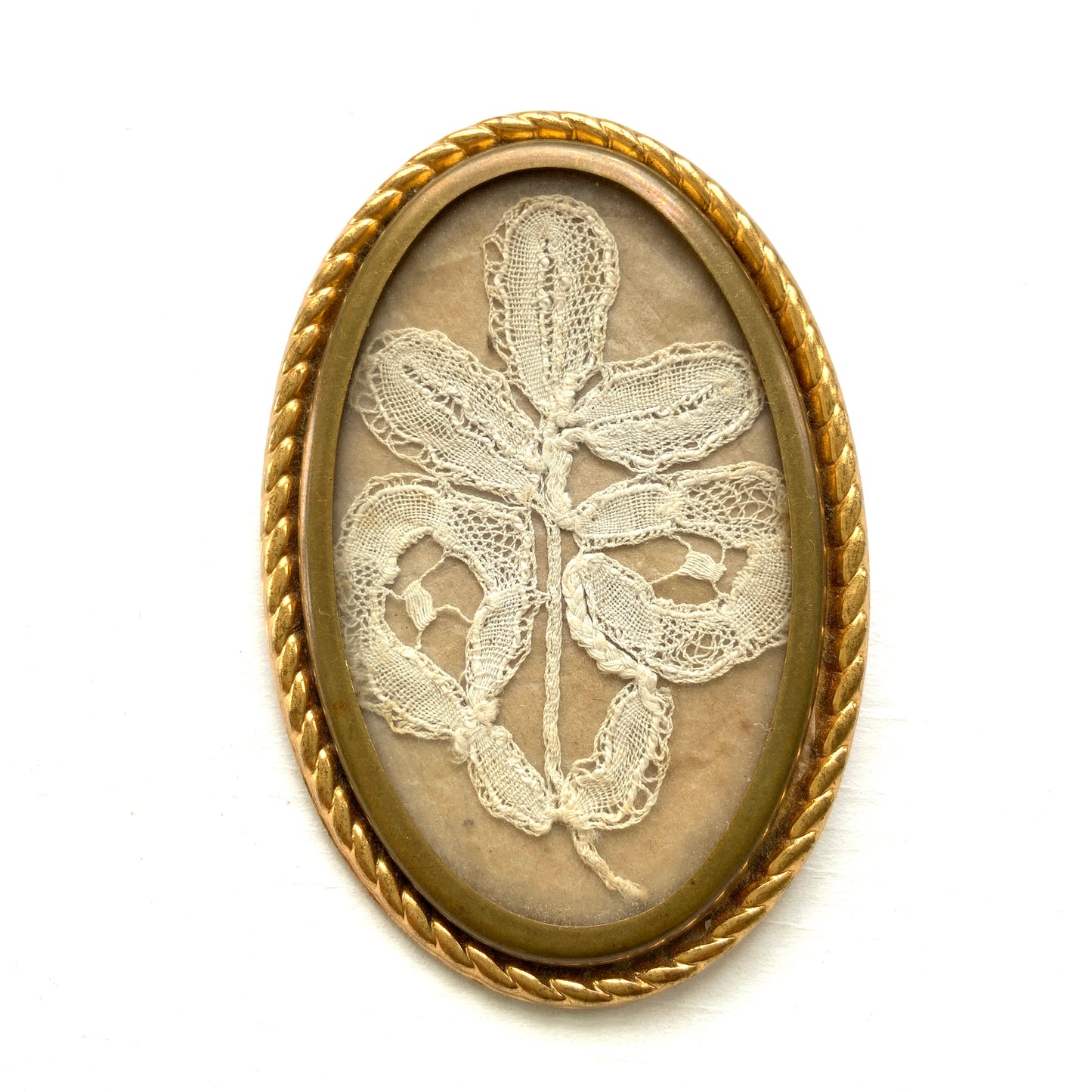 A delicate piece of lace is beautifully framed in a gold-tone setting. 繊細なレースがゴールドトーンのフレームに収められたブローチ。 