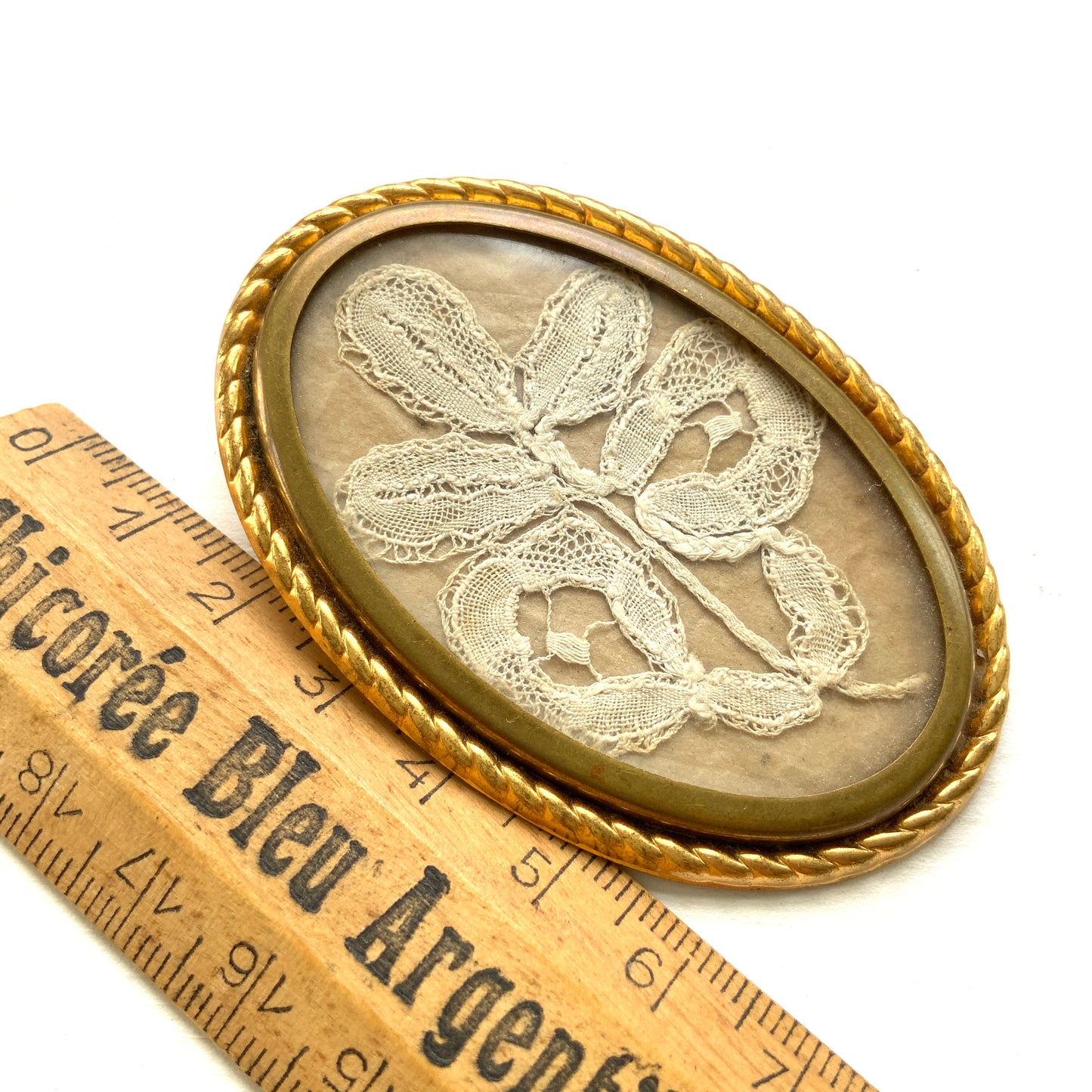 A delicate piece of lace is beautifully framed in a gold-tone setting. 繊細なレースがゴールドトーンのフレームに収められたブローチ。 