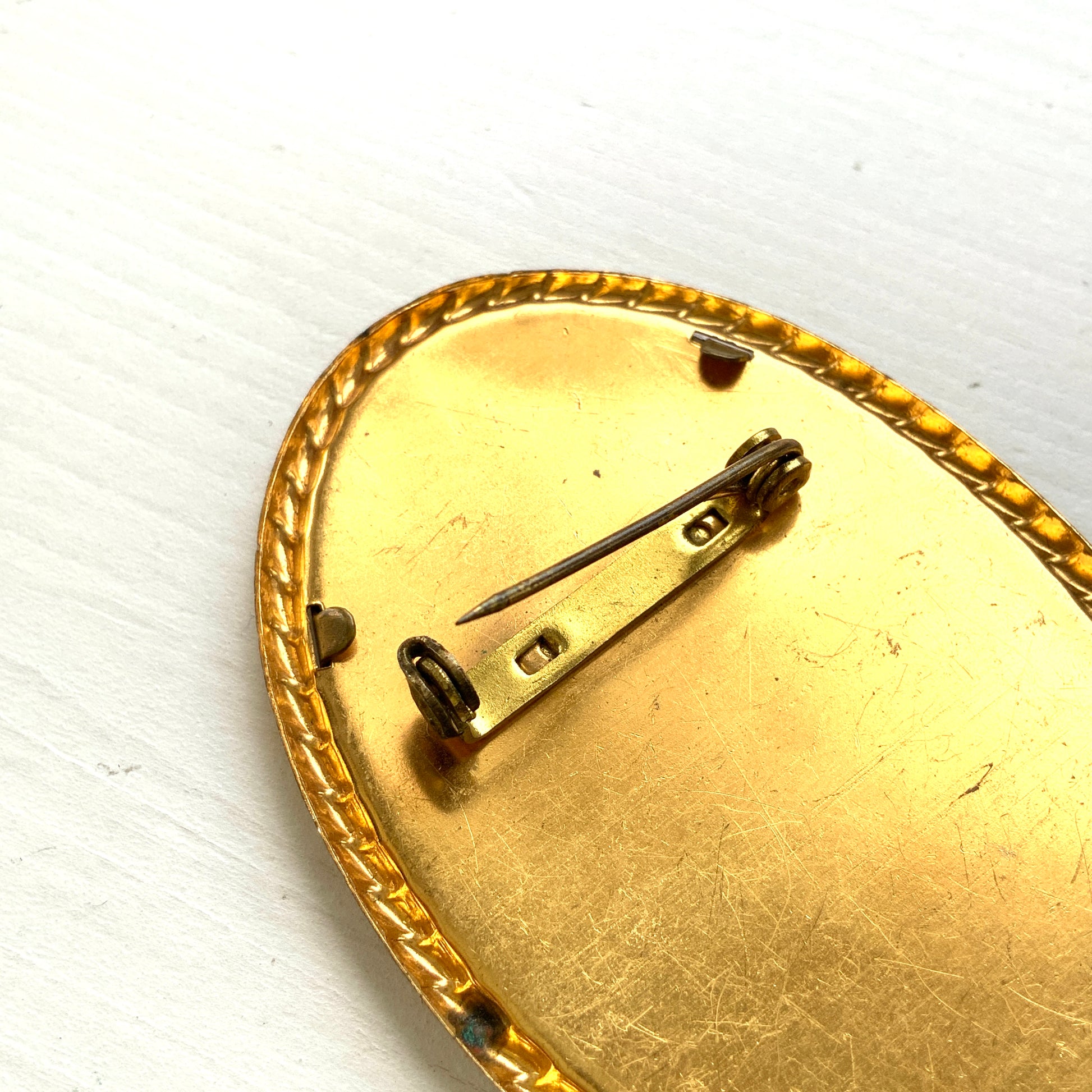 A delicate piece of lace is beautifully framed in a gold-tone setting. 繊細なレースがゴールドトーンのフレームに収められたブローチ。 