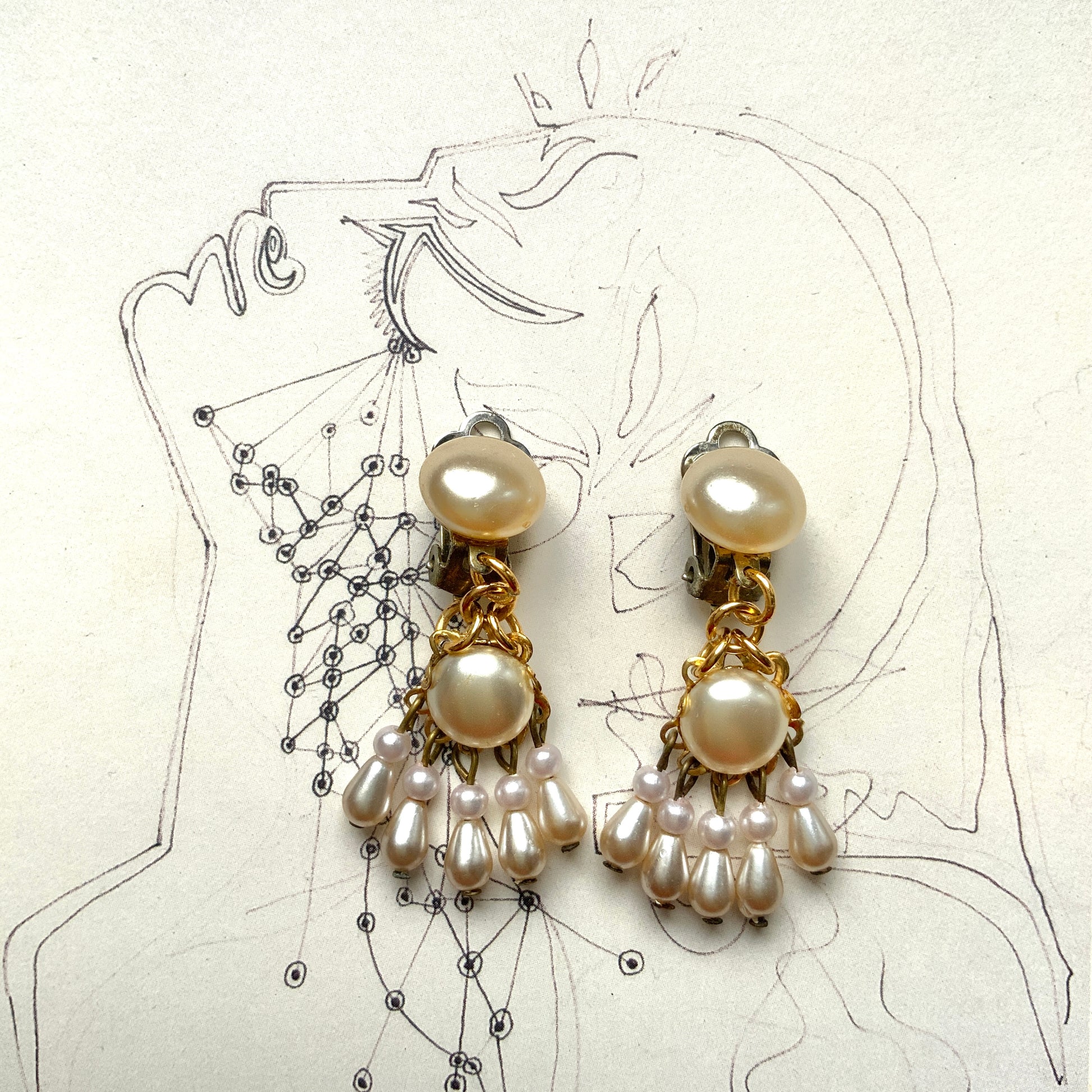 Clip earrings featuring button-shaped faux pearls with a fringe of many teardrop pearls. ボタン型フォーパールにたくさんのティアドロップパールのフリンジが揺れるクリップイヤリング。 