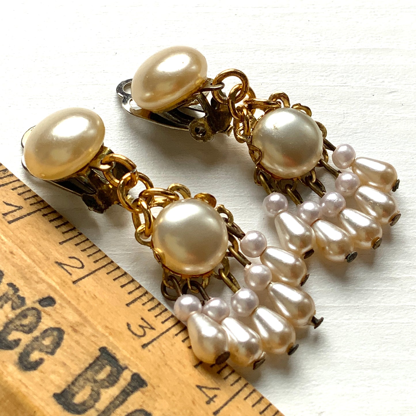 Clip earrings featuring button-shaped faux pearls with a fringe of many teardrop pearls. ボタン型フォーパールにたくさんのティアドロップパールのフリンジが揺れるクリップイヤリング。 