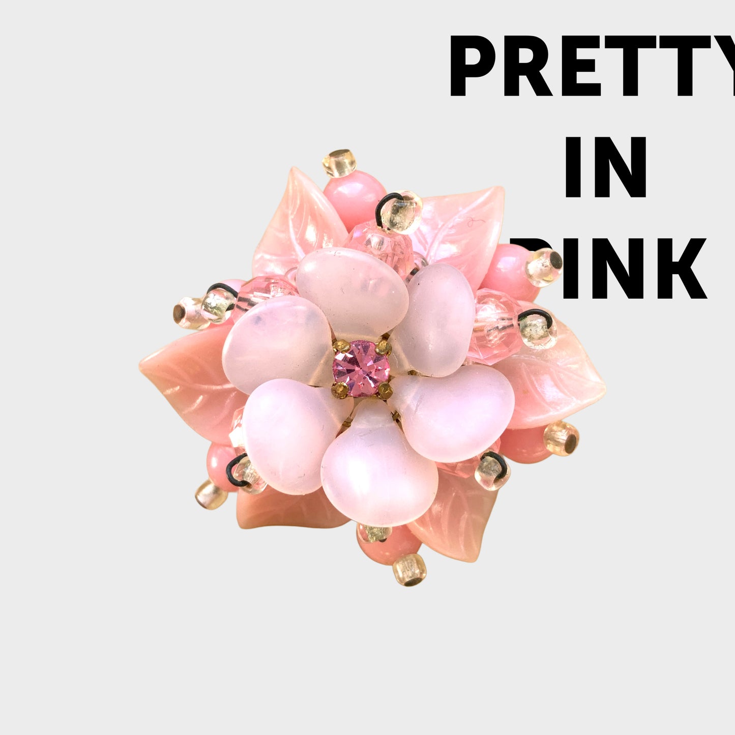 A floral brooch combining frosted glass, rhinestones, crystal beads and plastic elements.  フロストガラスやラインストーン、クリスタルビーズ、プラスチックなど、異なる素材を組み合わせたフラワーブローチ。