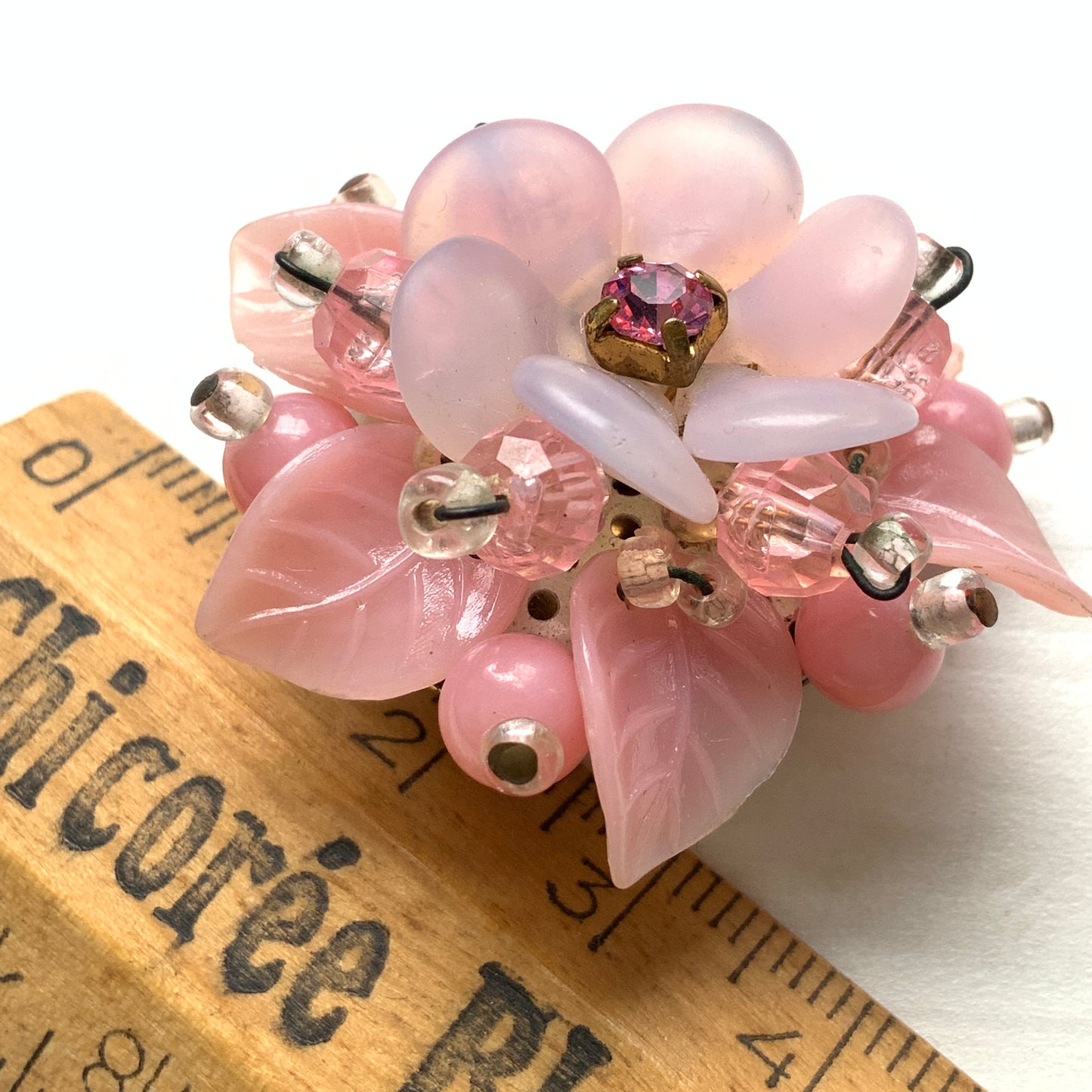 A floral brooch combining frosted glass, rhinestones, crystal beads and plastic elements.  フロストガラスやラインストーン、クリスタルビーズ、プラスチックなど、異なる素材を組み合わせたフラワーブローチ。