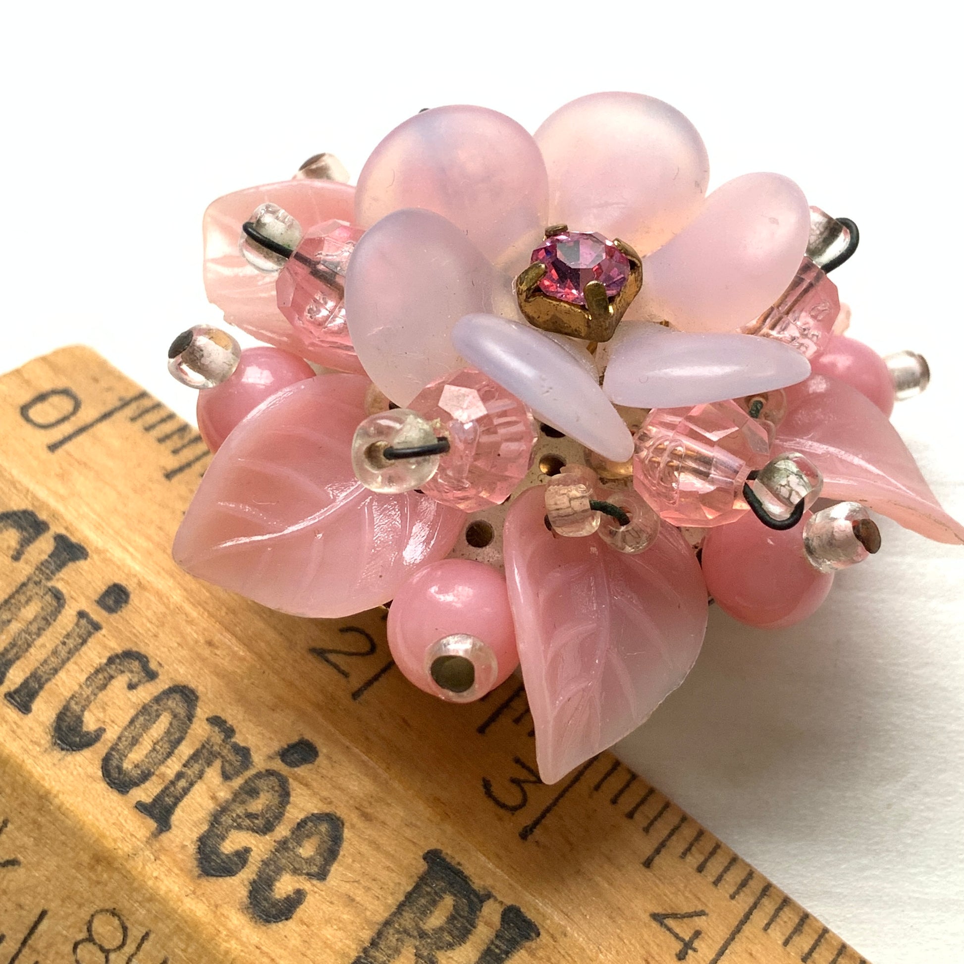 A floral brooch combining frosted glass, rhinestones, crystal beads and plastic elements.  フロストガラスやラインストーン、クリスタルビーズ、プラスチックなど、異なる素材を組み合わせたフラワーブローチ。