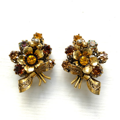 Clip-on earrings featuring a bouquet of gold-tone flowers adorned with amber, yellow, and orange rhinestones. ゴールドトーンのお花を、アンバー・イエロー・オレンジ系のラインストーンでブーケに仕立てたクリップイヤリング。 