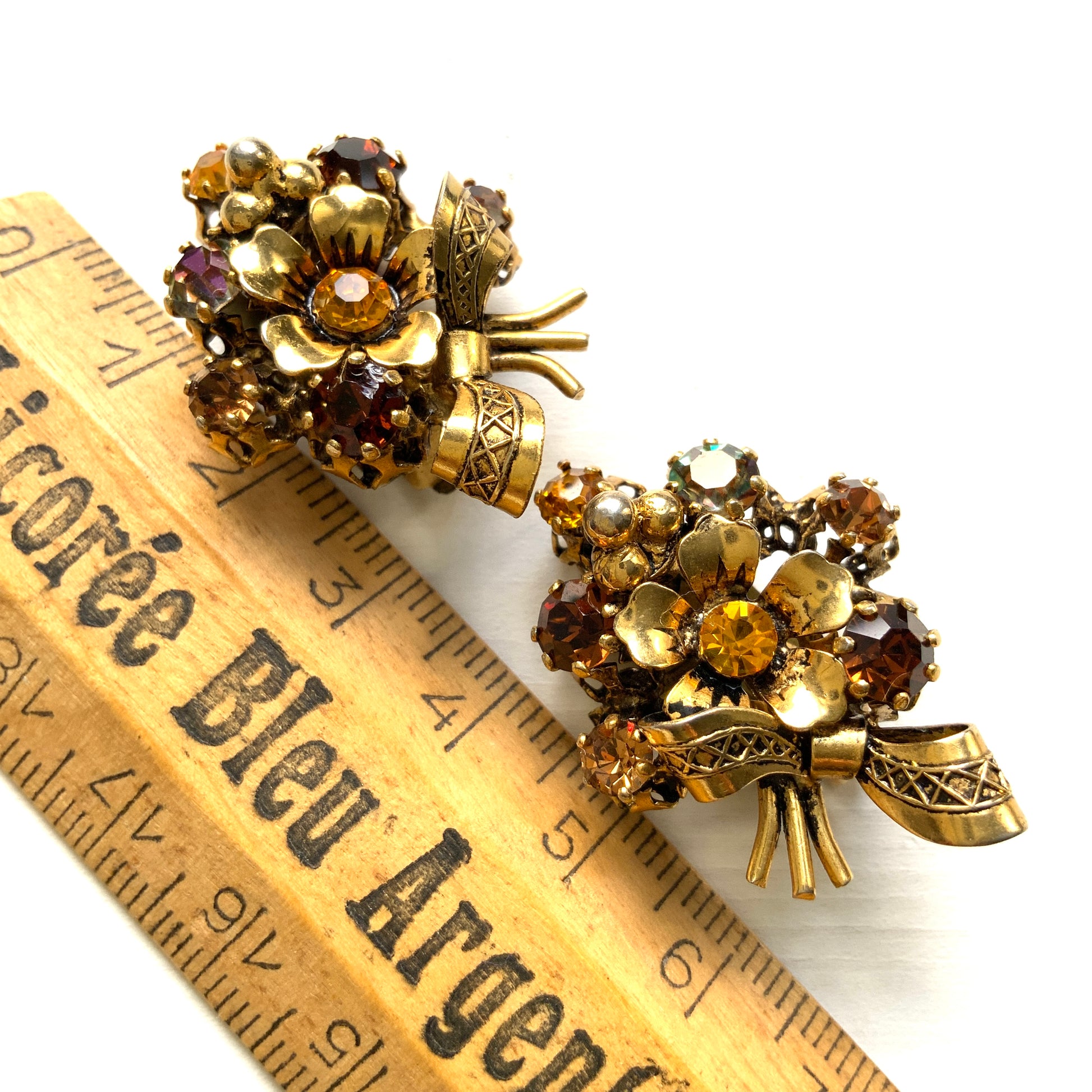 Clip-on earrings featuring a bouquet of gold-tone flowers adorned with amber, yellow, and orange rhinestones. ゴールドトーンのお花を、アンバー・イエロー・オレンジ系のラインストーンでブーケに仕立てたクリップイヤリング。 