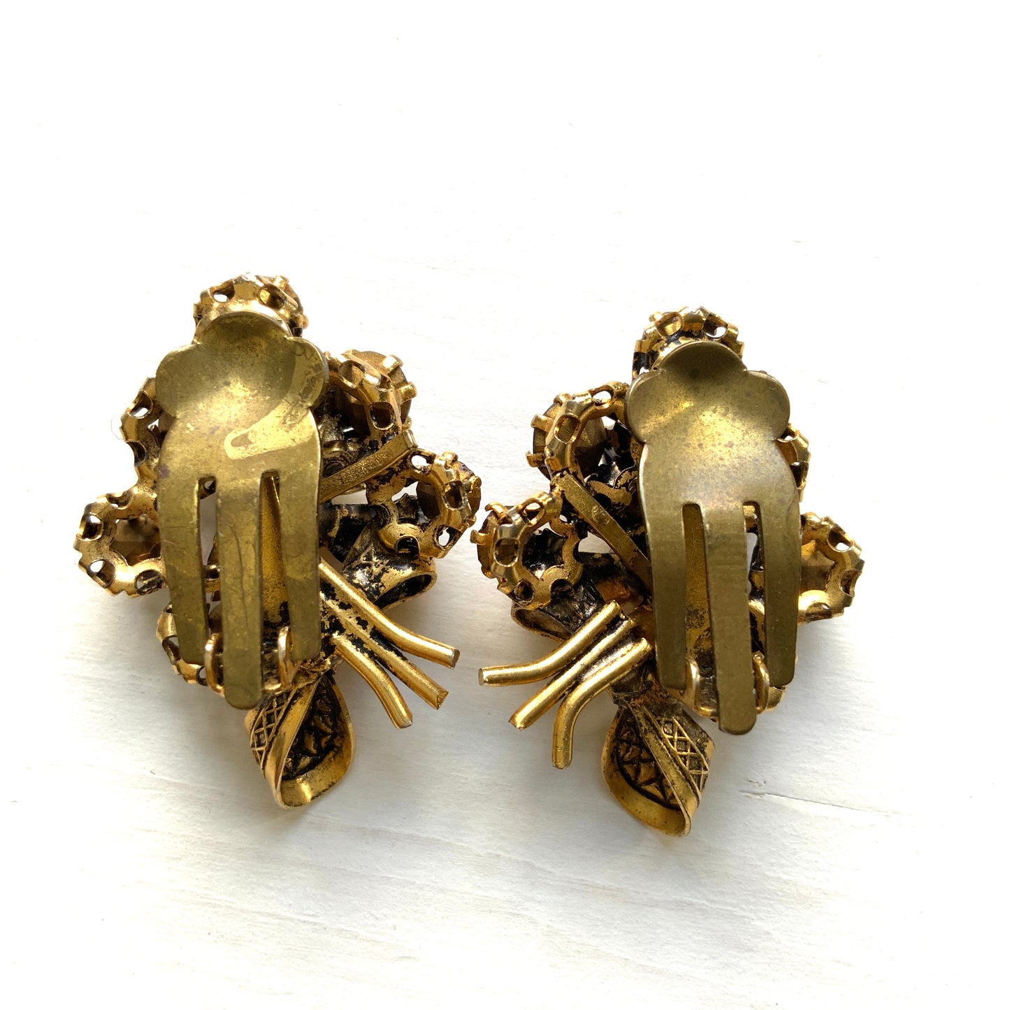 Clip-on earrings featuring a bouquet of gold-tone flowers adorned with amber, yellow, and orange rhinestones. ゴールドトーンのお花を、アンバー・イエロー・オレンジ系のラインストーンでブーケに仕立てたクリップイヤリング。 