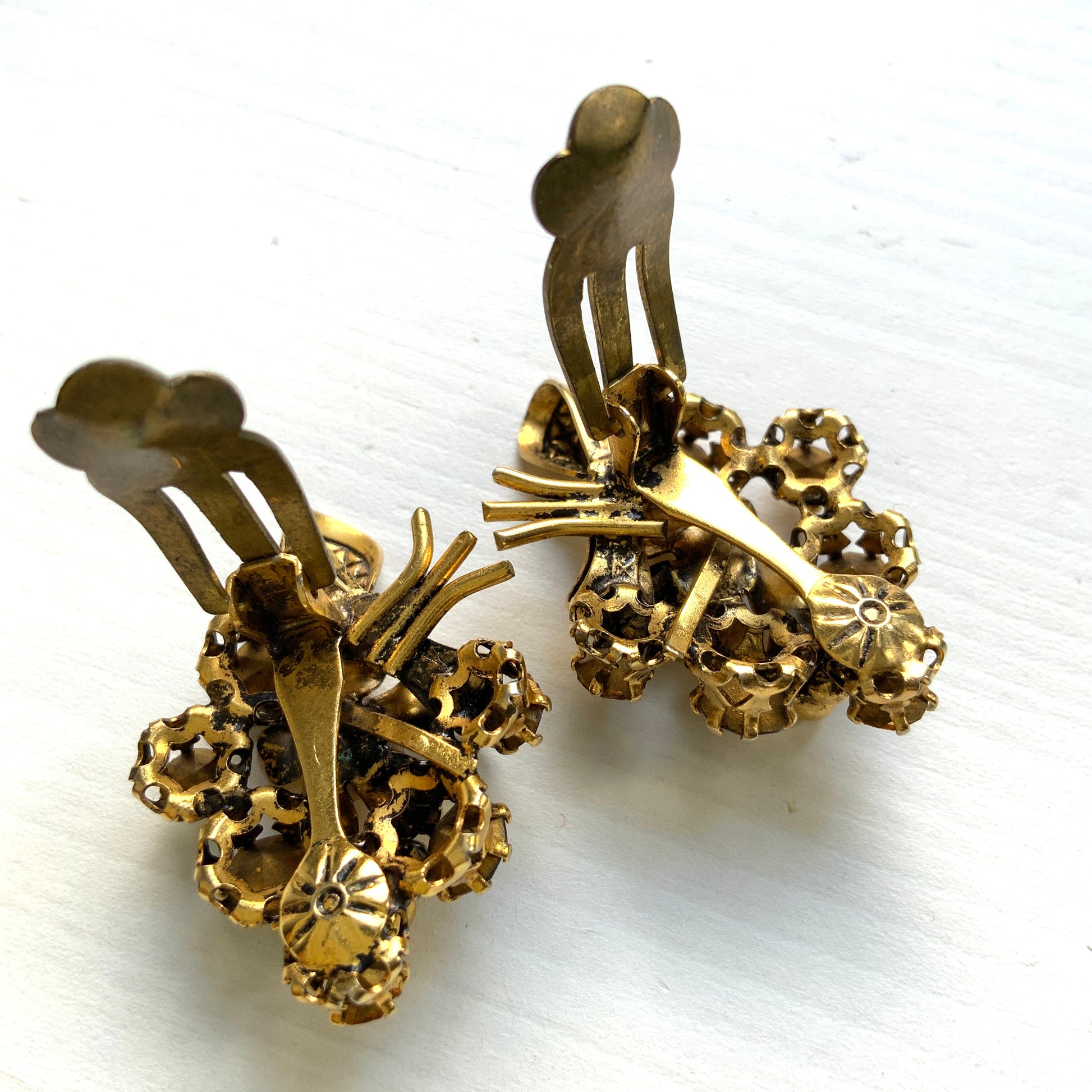Clip-on earrings featuring a bouquet of gold-tone flowers adorned with amber, yellow, and orange rhinestones. ゴールドトーンのお花を、アンバー・イエロー・オレンジ系のラインストーンでブーケに仕立てたクリップイヤリング。 