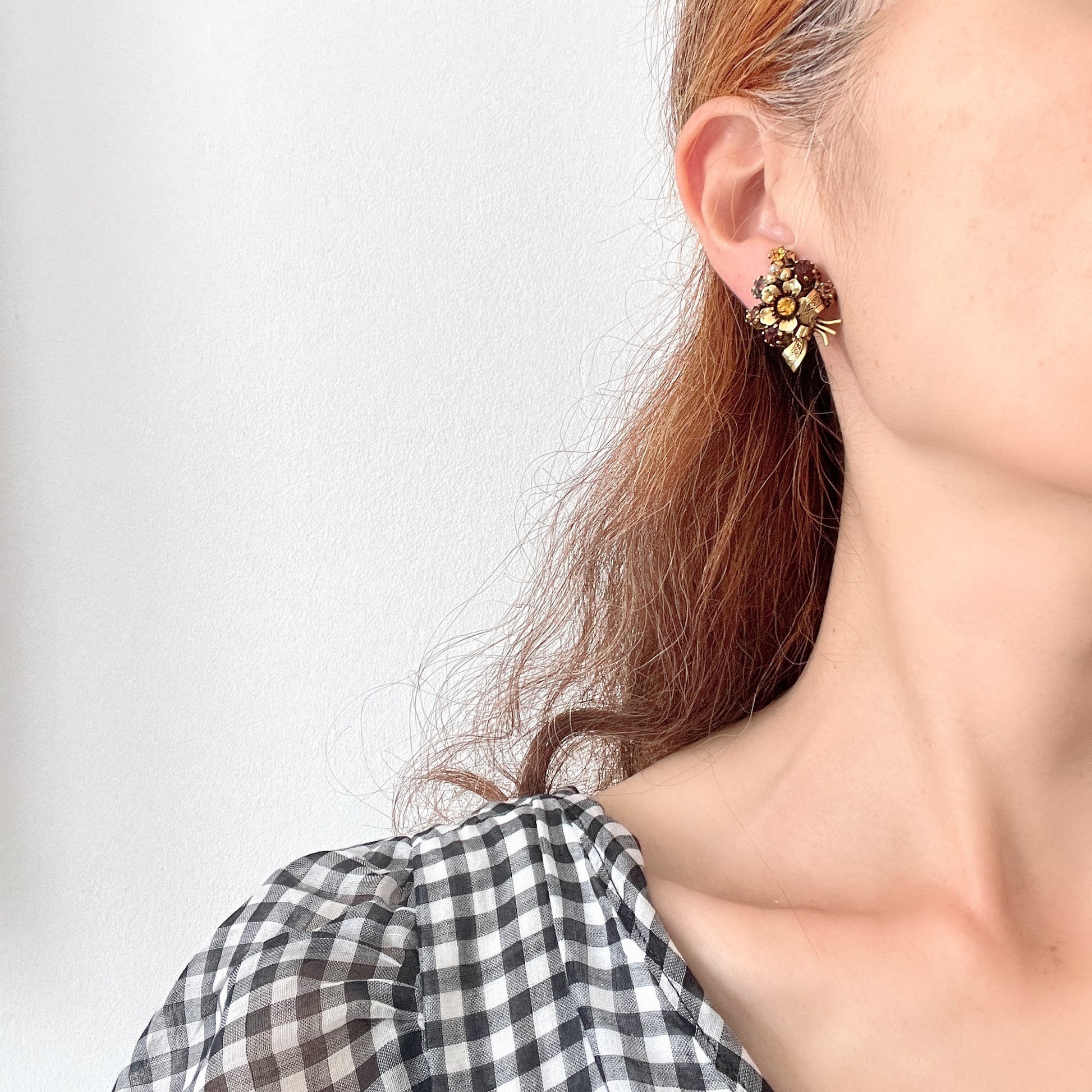 Clip-on earrings featuring a bouquet of gold-tone flowers adorned with amber, yellow, and orange rhinestones. ゴールドトーンのお花を、アンバー・イエロー・オレンジ系のラインストーンでブーケに仕立てたクリップイヤリング。 