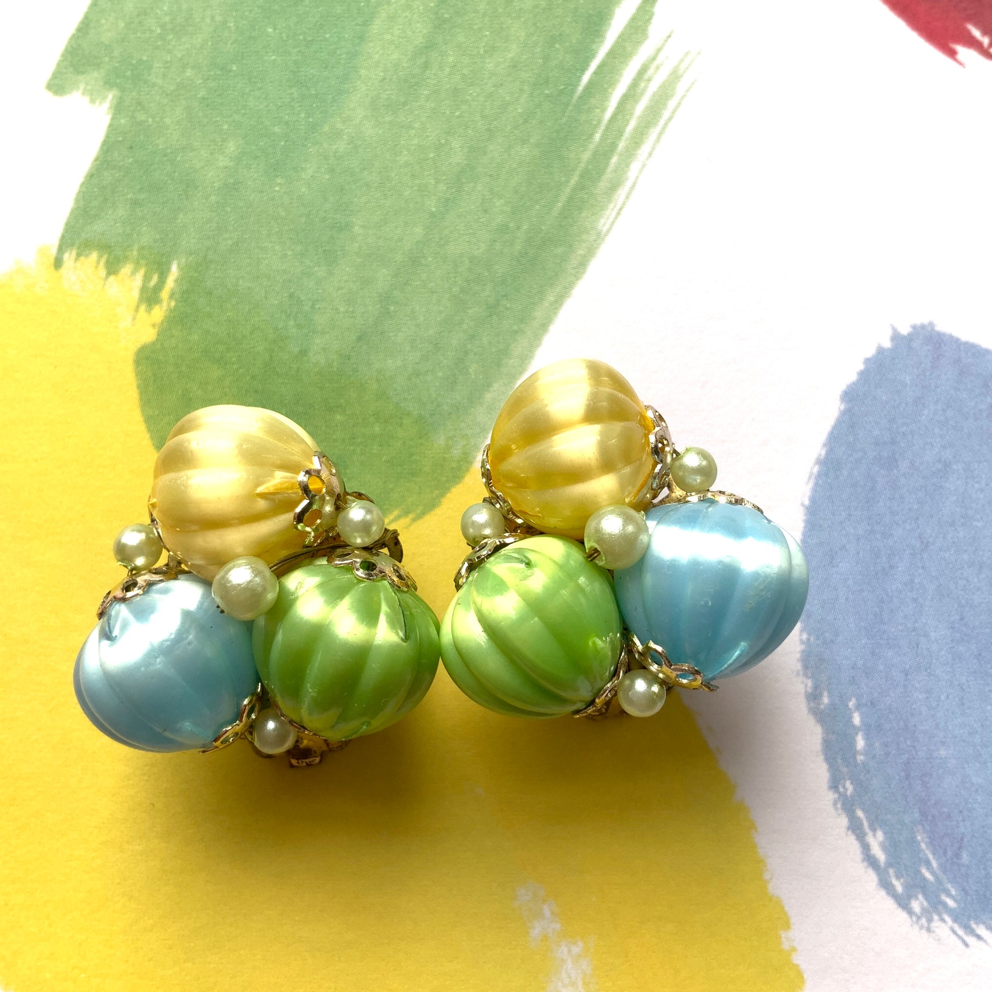  Clip-on earrings featuring soft pastel-coloured satin plastic beads in yellow, blue, and green. イエロー、ブルー、グリーンの柔らかいパステルカラーのサテンプラスチックビーズのクリップイヤリング。