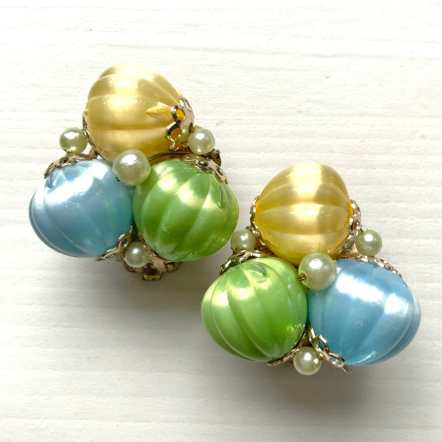  Clip-on earrings featuring soft pastel-coloured satin plastic beads in yellow, blue, and green. イエロー、ブルー、グリーンの柔らかいパステルカラーのサテンプラスチックビーズのクリップイヤリング。