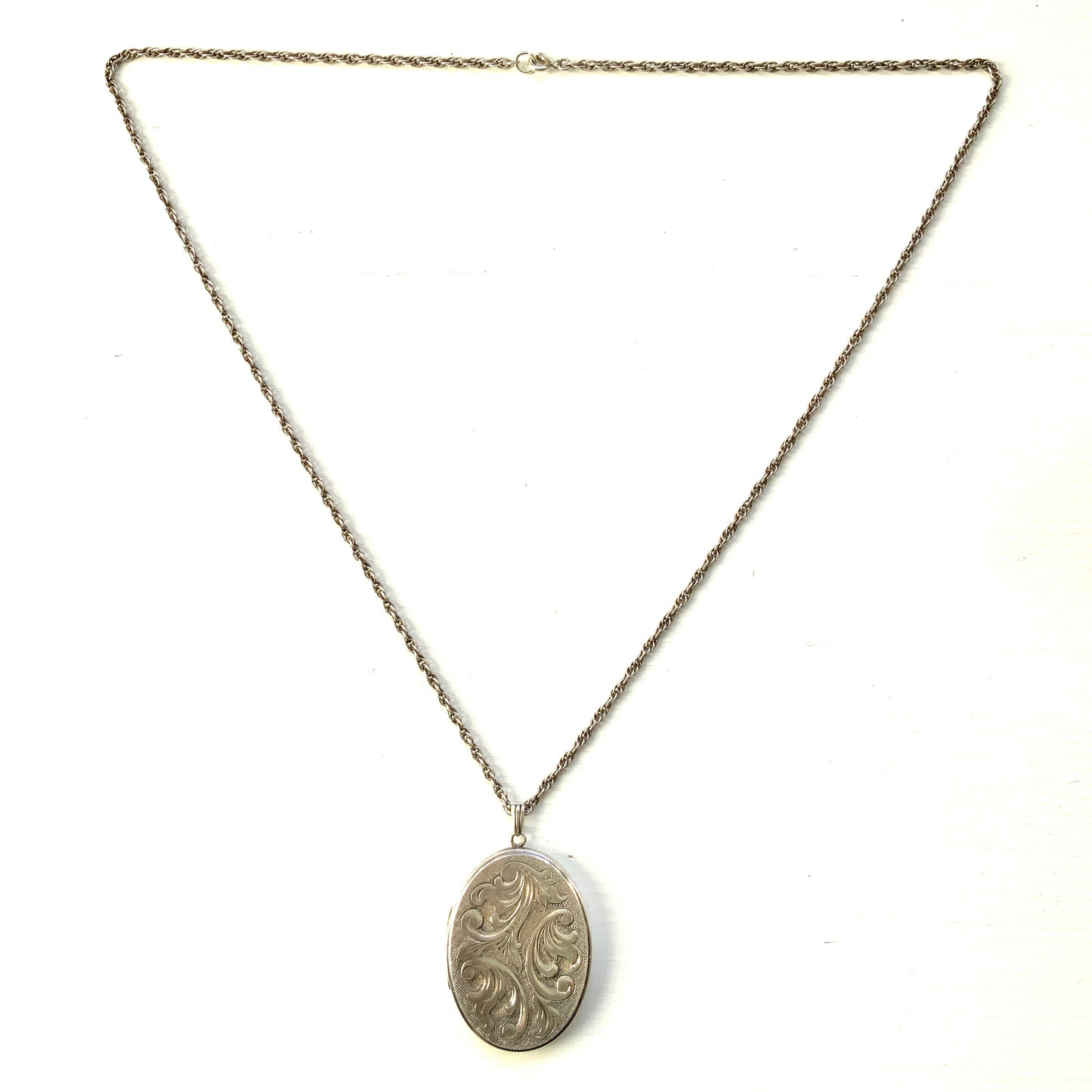 A silver locket necklace beautifully engraved with an elegant botanical motif.  美しい植物模様が彫られた、シルバーのロケットネックレス。