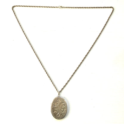 A silver locket necklace beautifully engraved with an elegant botanical motif.  美しい植物模様が彫られた、シルバーのロケットネックレス。