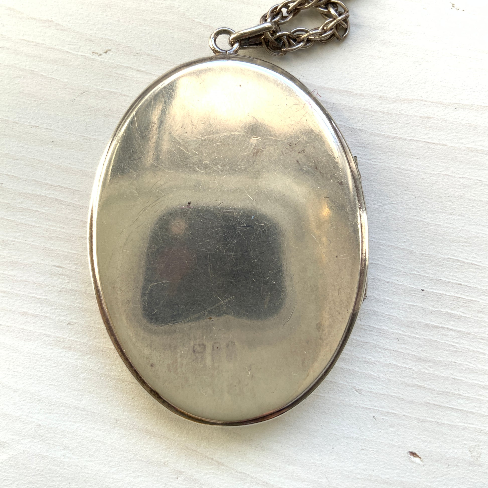 A silver locket necklace beautifully engraved with an elegant botanical motif.  美しい植物模様が彫られた、シルバーのロケットネックレス。