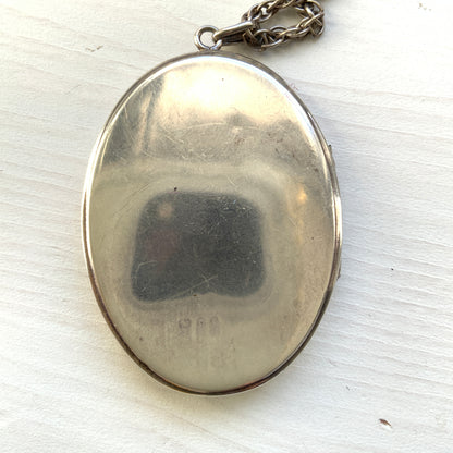 A silver locket necklace beautifully engraved with an elegant botanical motif.  美しい植物模様が彫られた、シルバーのロケットネックレス。