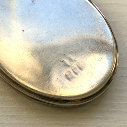 A silver locket necklace beautifully engraved with an elegant botanical motif.  美しい植物模様が彫られた、シルバーのロケットネックレス。