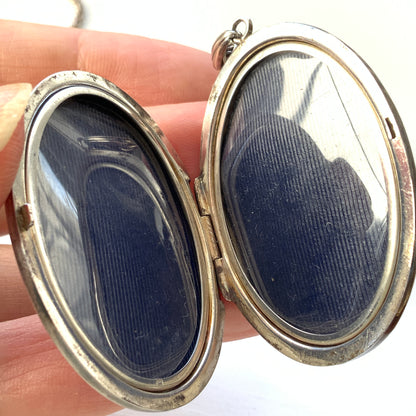 A silver locket necklace beautifully engraved with an elegant botanical motif.  美しい植物模様が彫られた、シルバーのロケットネックレス。