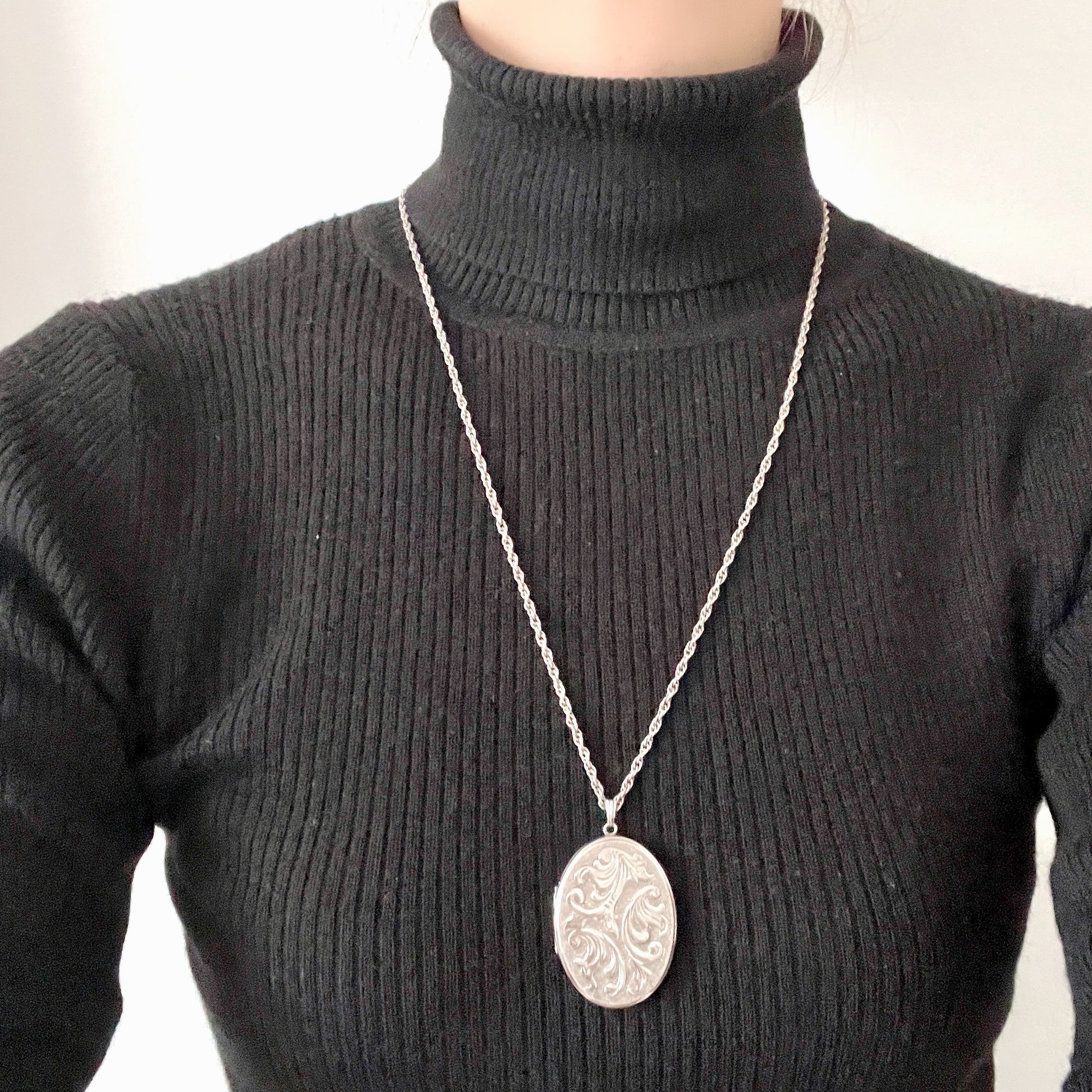 A silver locket necklace beautifully engraved with an elegant botanical motif.  美しい植物模様が彫られた、シルバーのロケットネックレス。