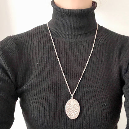 A silver locket necklace beautifully engraved with an elegant botanical motif.  美しい植物模様が彫られた、シルバーのロケットネックレス。