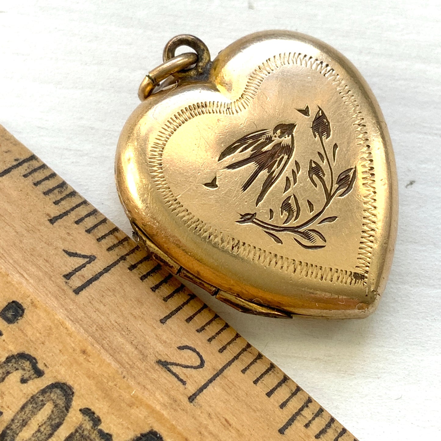 A heart-shaped rolled gold locket engraved with a charming swallow motif. かわいらしいツバメが彫られた、ハート型のロールドゴールドのロケット。