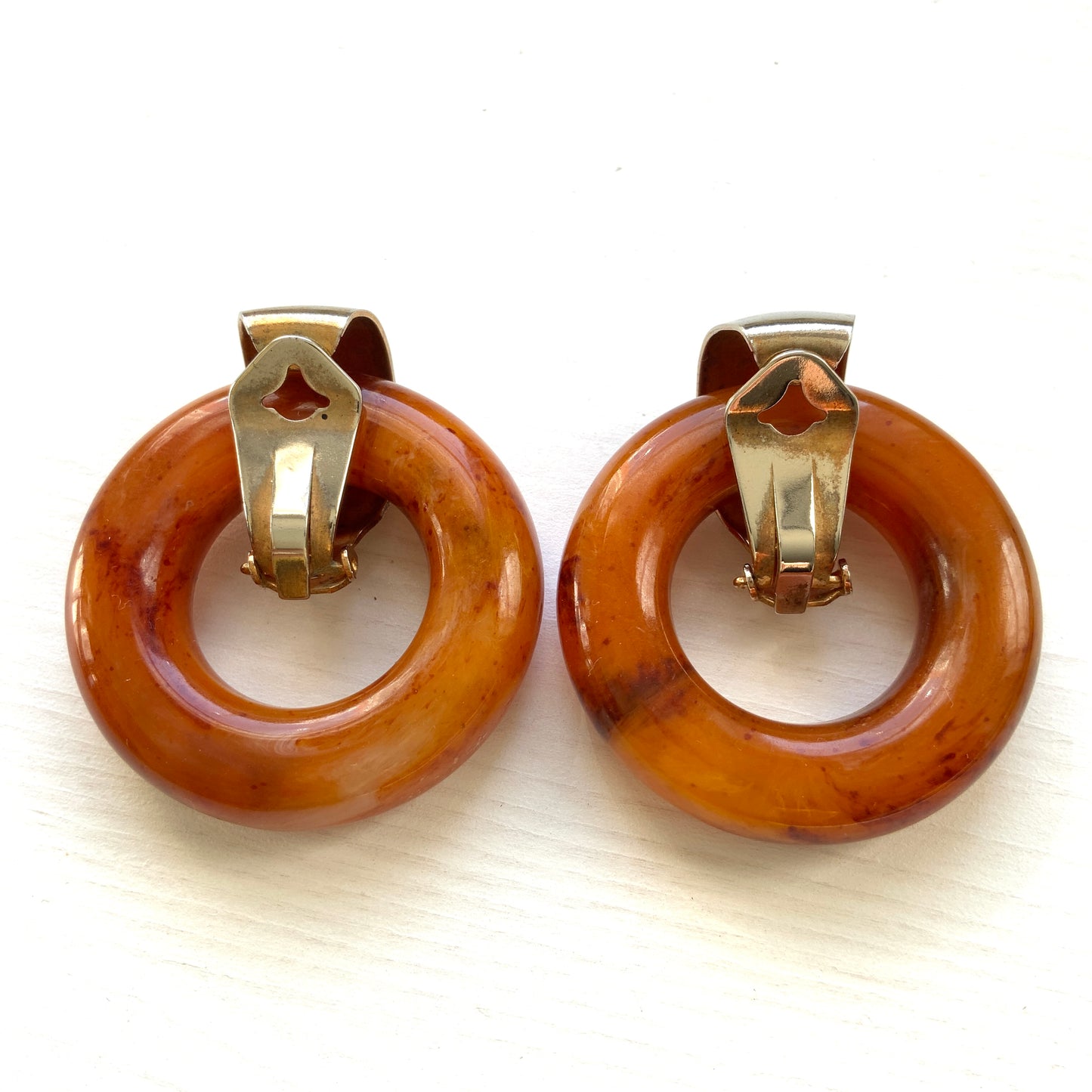 Clip-on door knocker earrings featuring amber-coloured plastic hoops. アンバーカラーのプラスチックフープが揺れる、ドアノッカータイプのクリップイヤリング。