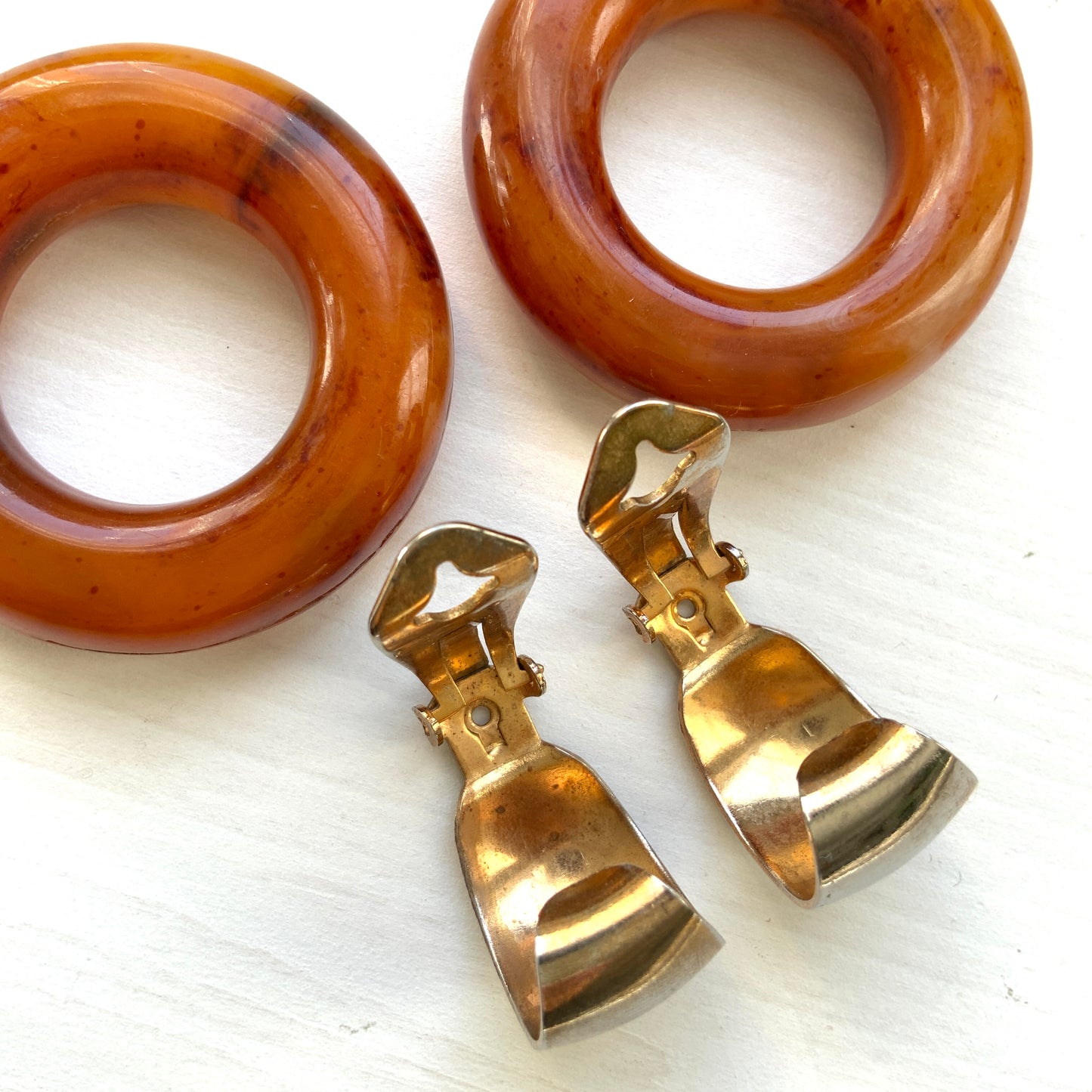Clip-on door knocker earrings featuring amber-coloured plastic hoops. アンバーカラーのプラスチックフープが揺れる、ドアノッカータイプのクリップイヤリング。