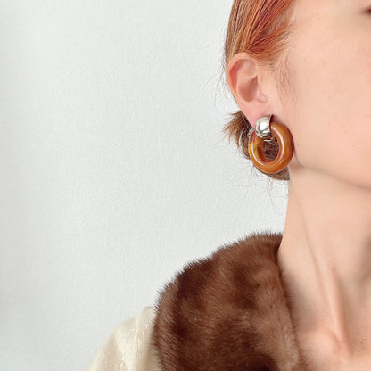 Clip-on door knocker earrings featuring amber-coloured plastic hoops. アンバーカラーのプラスチックフープが揺れる、ドアノッカータイプのクリップイヤリング。