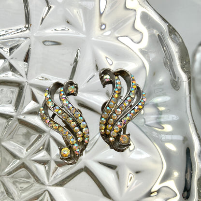 Clip-on earrings featuring aurora borealis rhinestones that trace a graceful curved line. 虹色に輝くオーロラストーンが緩やかなラインを描くクリップイヤリング。
