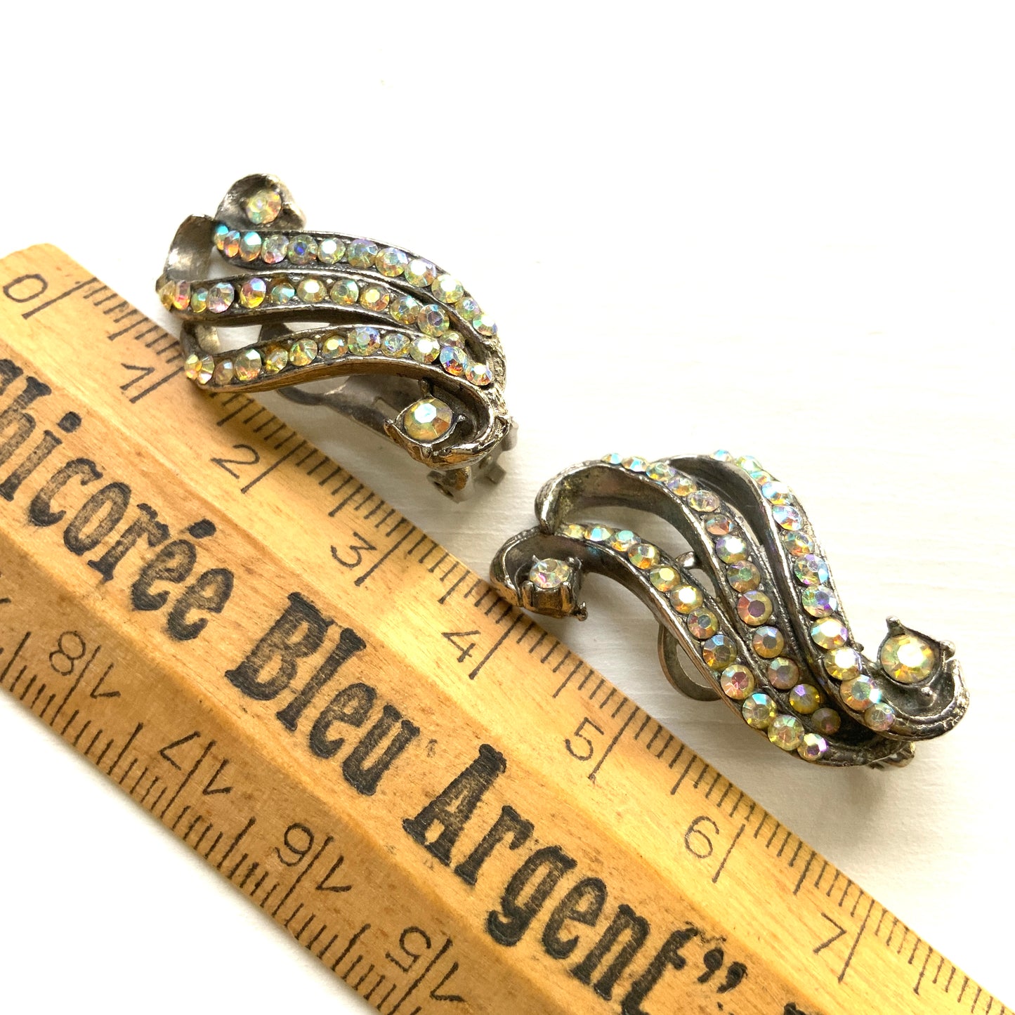 Clip-on earrings featuring aurora borealis rhinestones that trace a graceful curved line. 虹色に輝くオーロラストーンが緩やかなラインを描くクリップイヤリング。