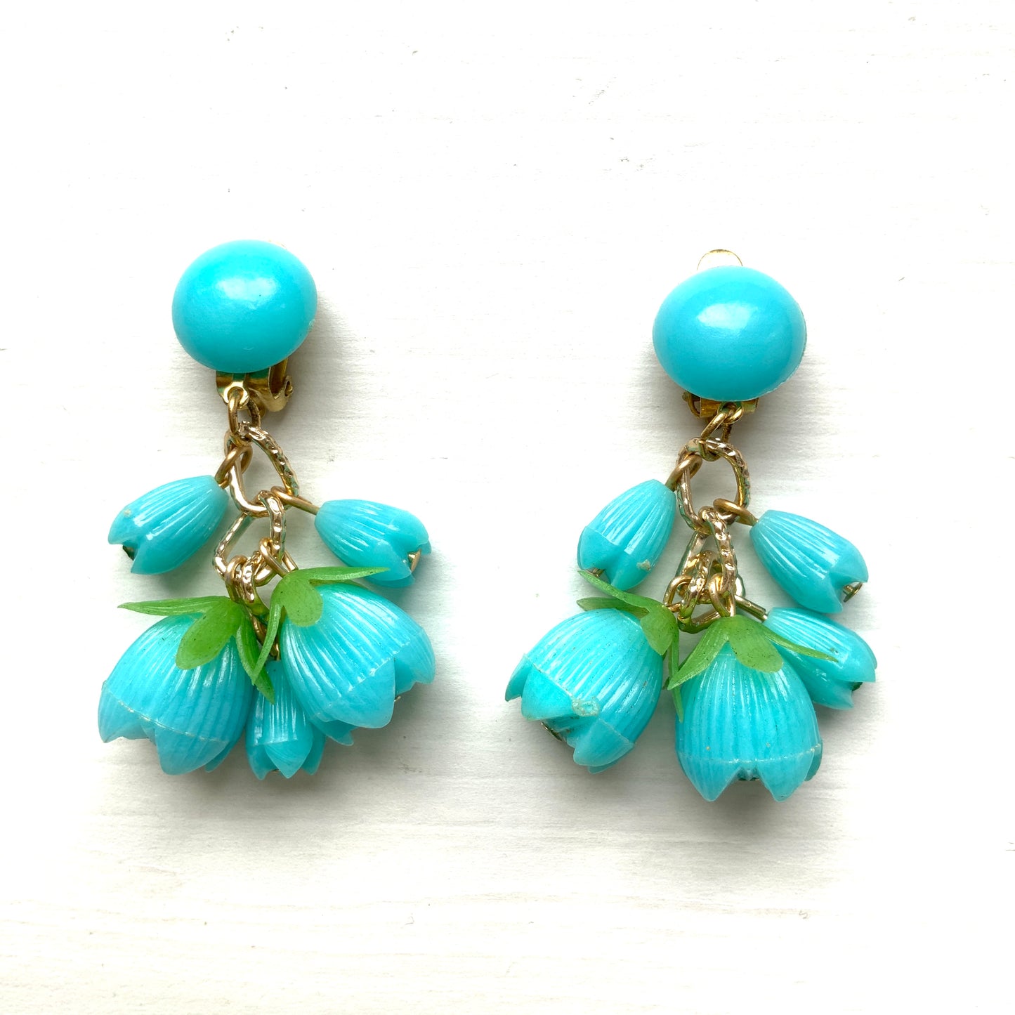 A pair of vintage clip-on earrings featuring dangling turquoise blue plastic flower beads. ターコイズブルーのプラスチックフラワービーズが揺れるヴィンテージクリップイヤリング。