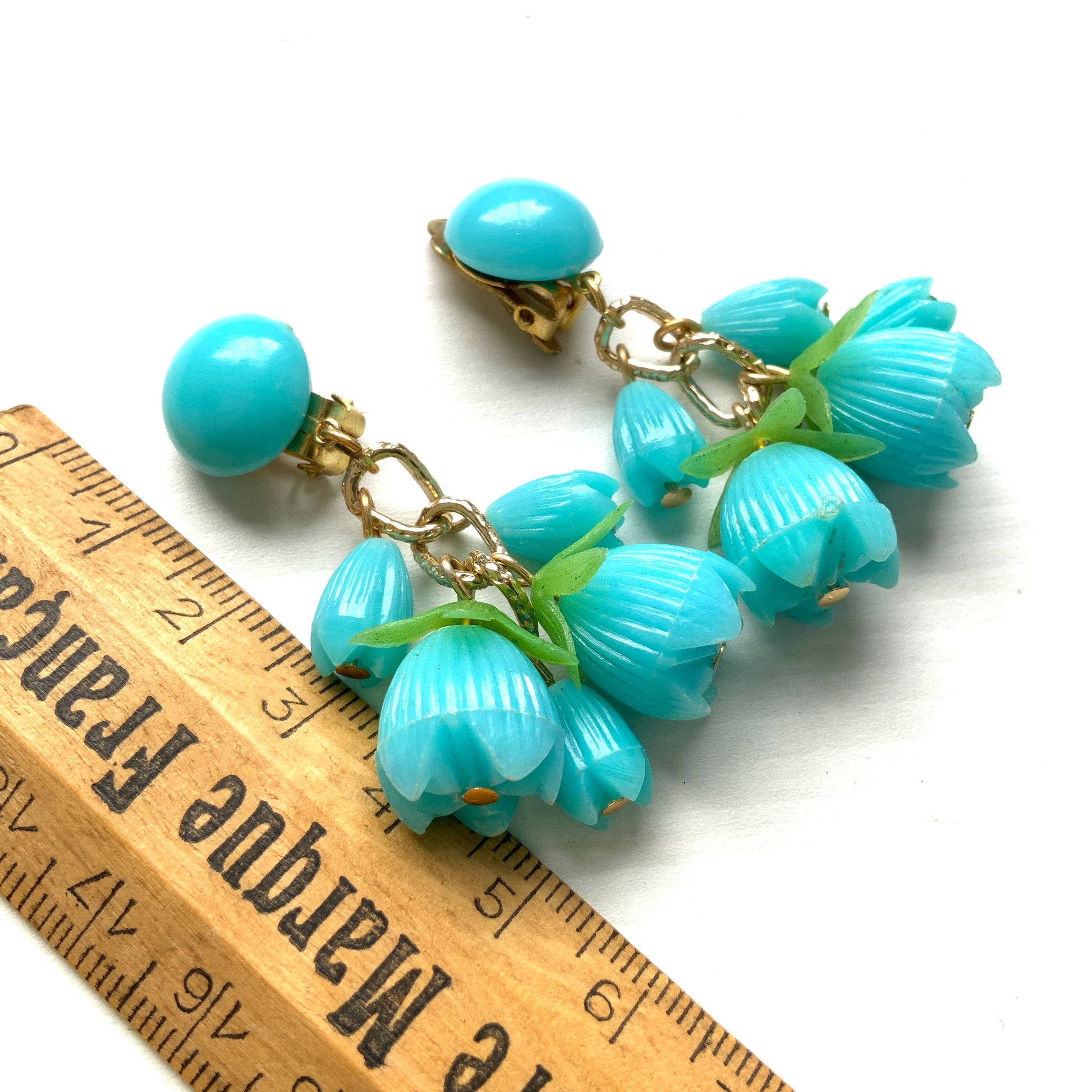 A pair of vintage clip-on earrings featuring dangling turquoise blue plastic flower beads. ターコイズブルーのプラスチックフラワービーズが揺れるヴィンテージクリップイヤリング。