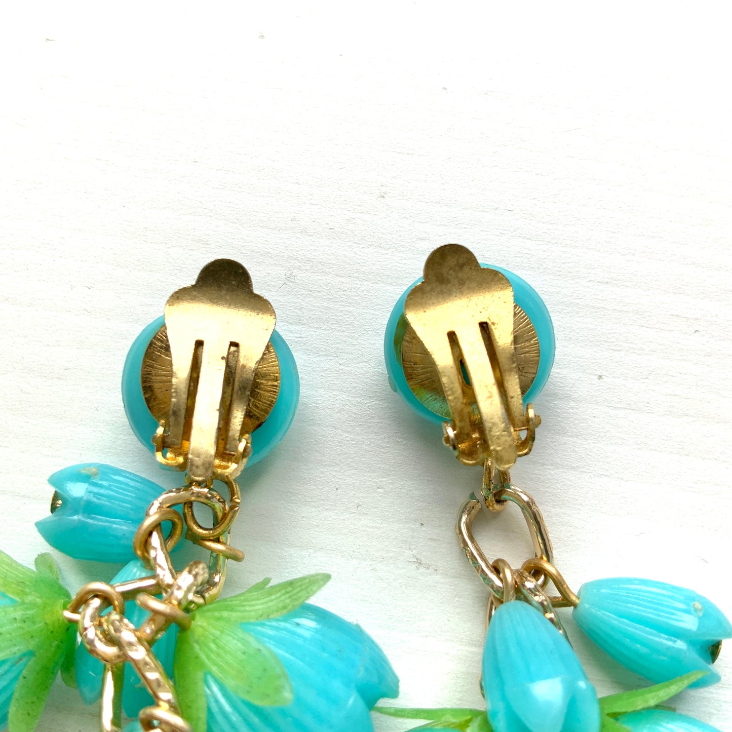 A pair of vintage clip-on earrings featuring dangling turquoise blue plastic flower beads. ターコイズブルーのプラスチックフラワービーズが揺れるヴィンテージクリップイヤリング。