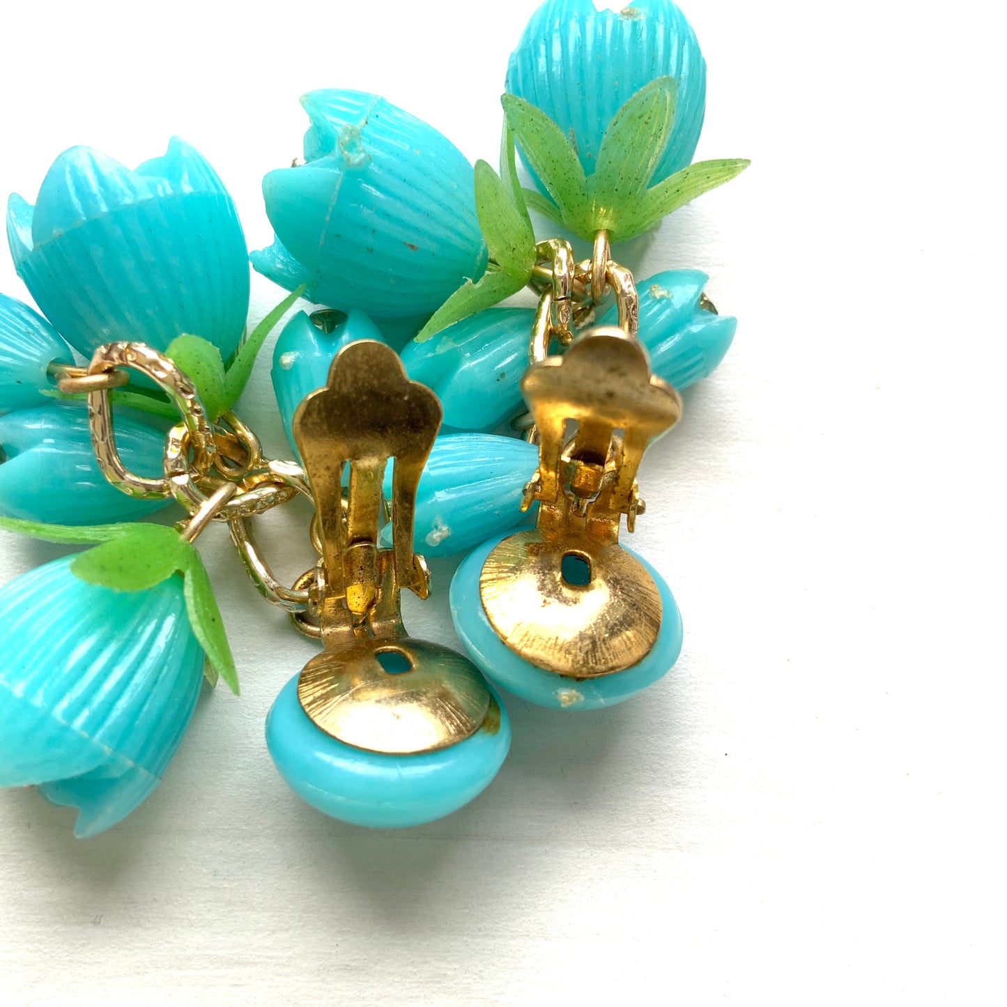 A pair of vintage clip-on earrings featuring dangling turquoise blue plastic flower beads. ターコイズブルーのプラスチックフラワービーズが揺れるヴィンテージクリップイヤリング。