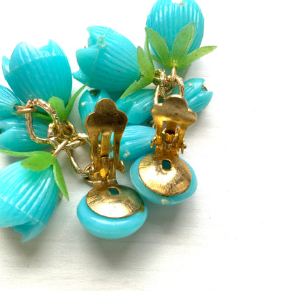 A pair of vintage clip-on earrings featuring dangling turquoise blue plastic flower beads. ターコイズブルーのプラスチックフラワービーズが揺れるヴィンテージクリップイヤリング。