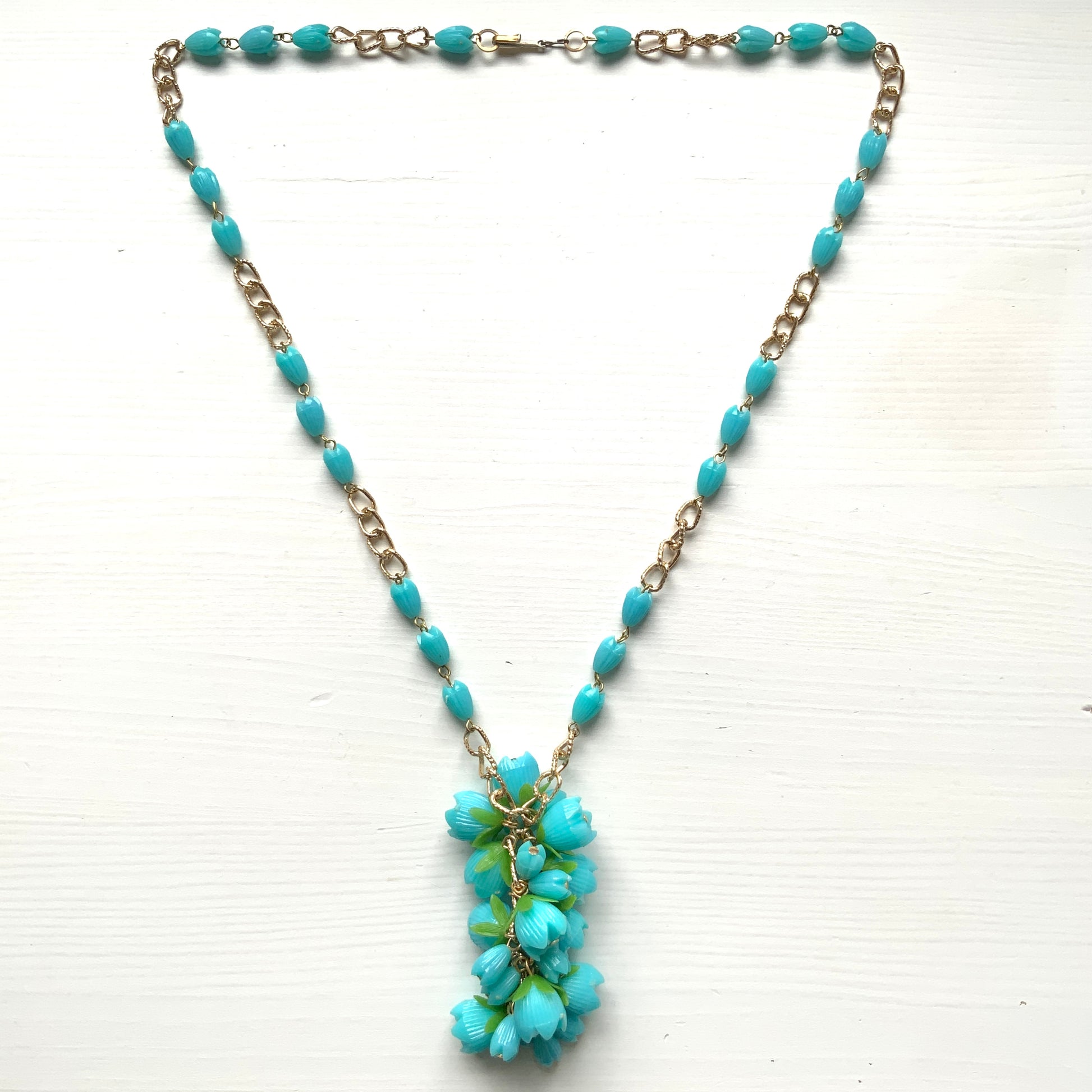 A vintage necklace featuring turquoise blue plastic flower beads that sway beautifully at the neckline.  ターコイズブルーのプラスチックフラワービーズが胸元で揺れるヴィンテージネックレス。
