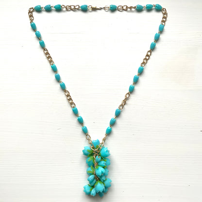 A vintage necklace featuring turquoise blue plastic flower beads that sway beautifully at the neckline.  ターコイズブルーのプラスチックフラワービーズが胸元で揺れるヴィンテージネックレス。