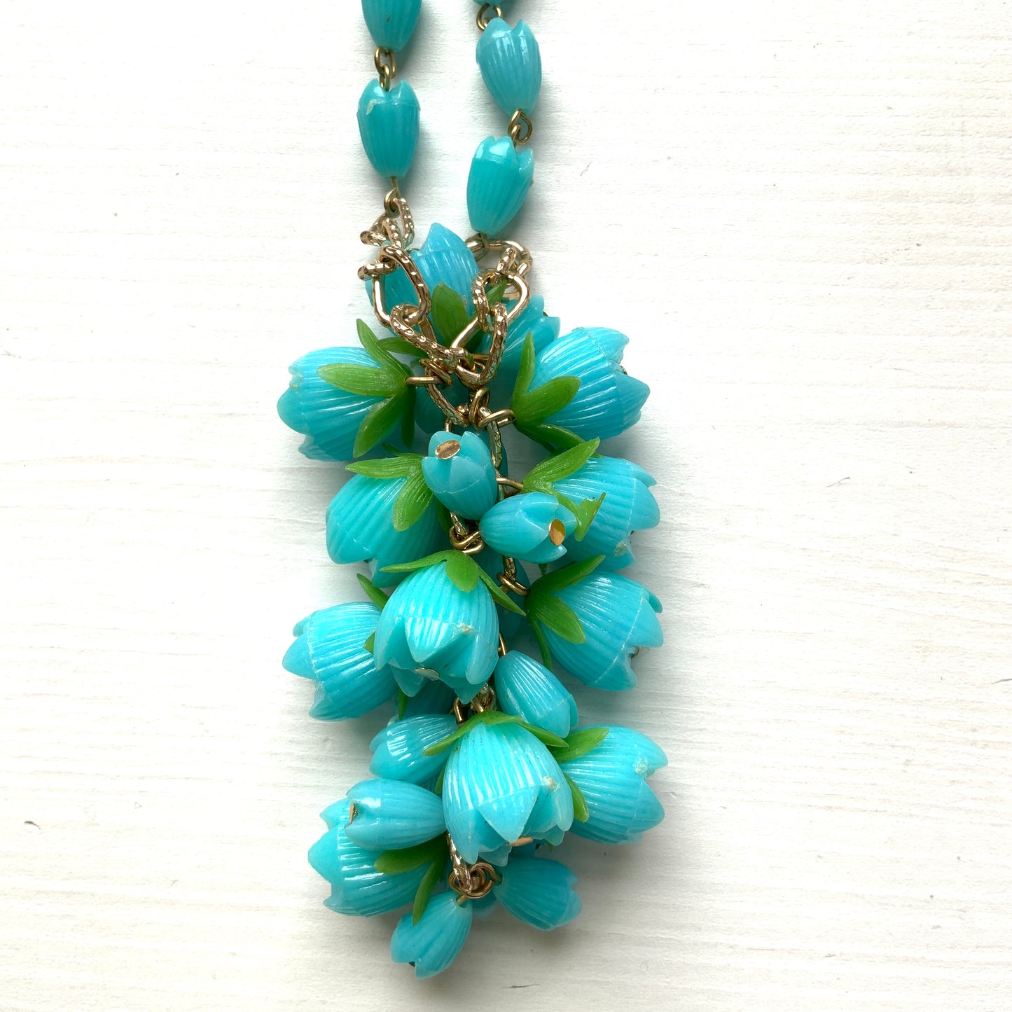 A vintage necklace featuring turquoise blue plastic flower beads that sway beautifully at the neckline.  ターコイズブルーのプラスチックフラワービーズが胸元で揺れるヴィンテージネックレス。