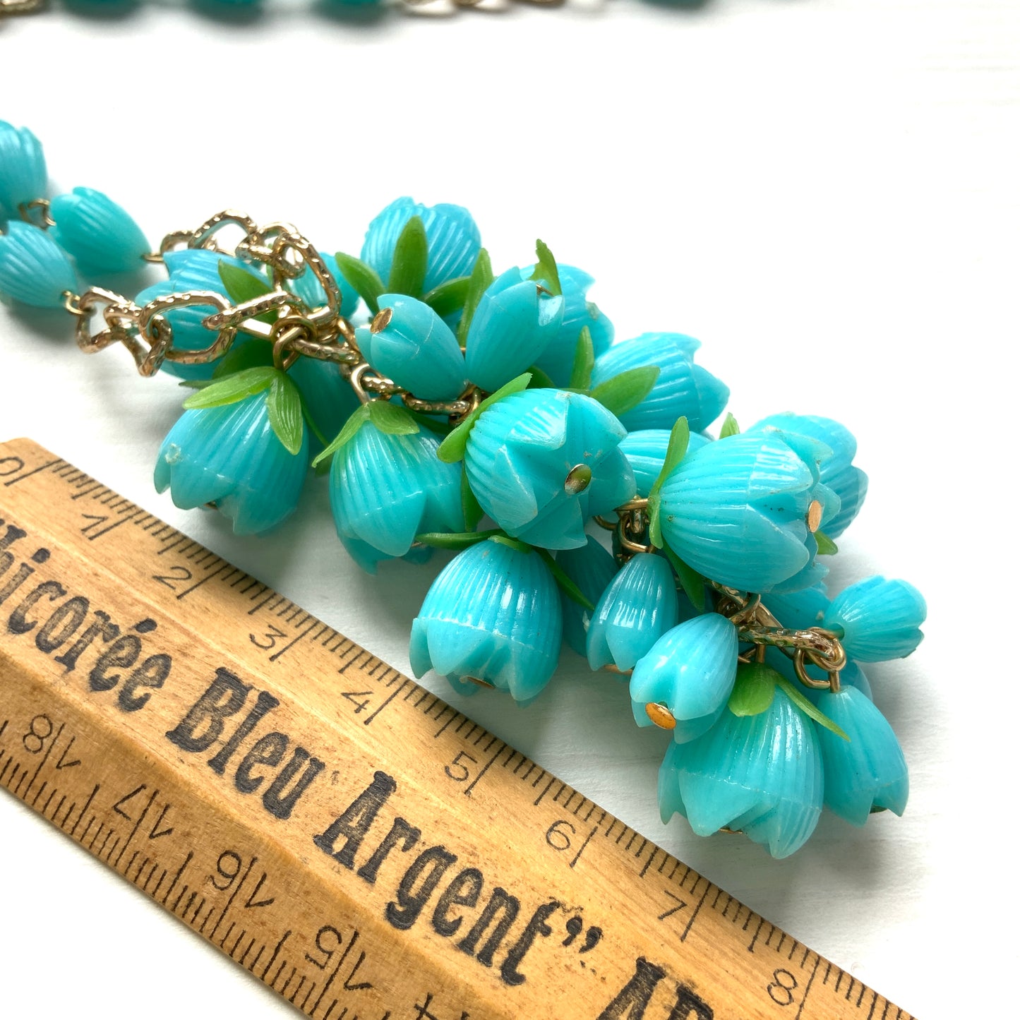 A vintage necklace featuring turquoise blue plastic flower beads that sway beautifully at the neckline.  ターコイズブルーのプラスチックフラワービーズが胸元で揺れるヴィンテージネックレス。
